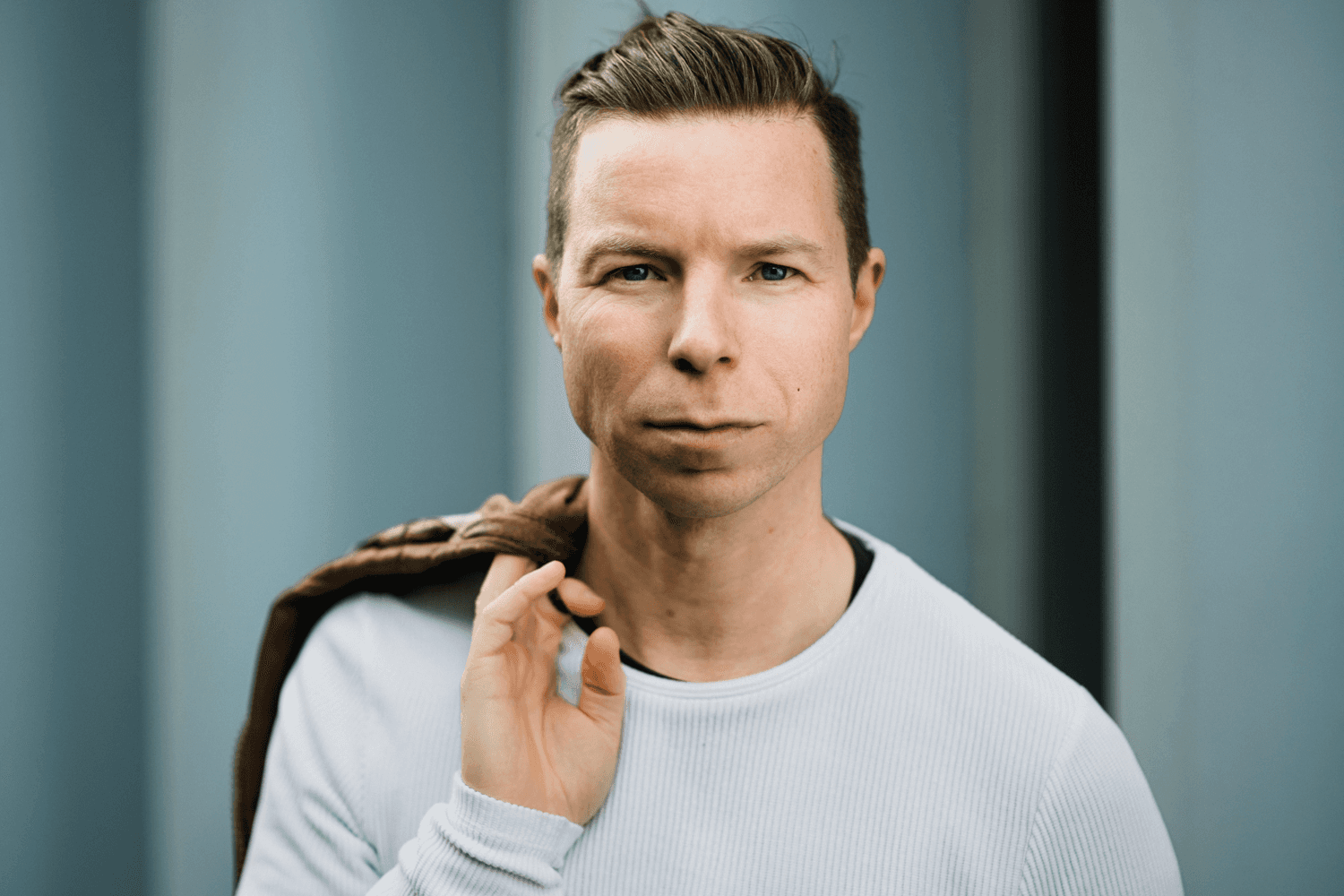 headshot casting photo of Eli Thorne, actor, fair-haired man in white shirt, blue studio background.