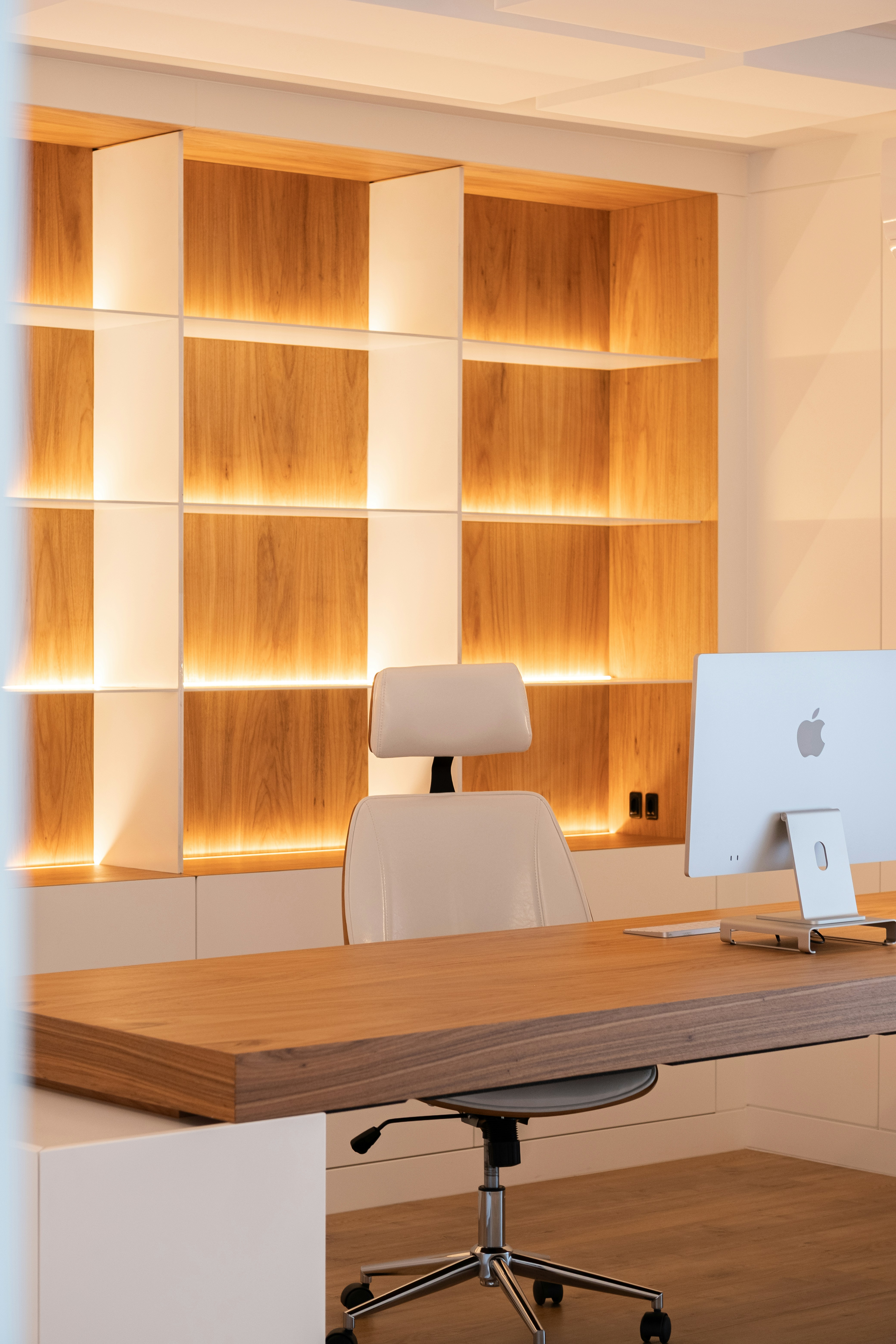 Modern office with wooden desk and illuminated shelves
