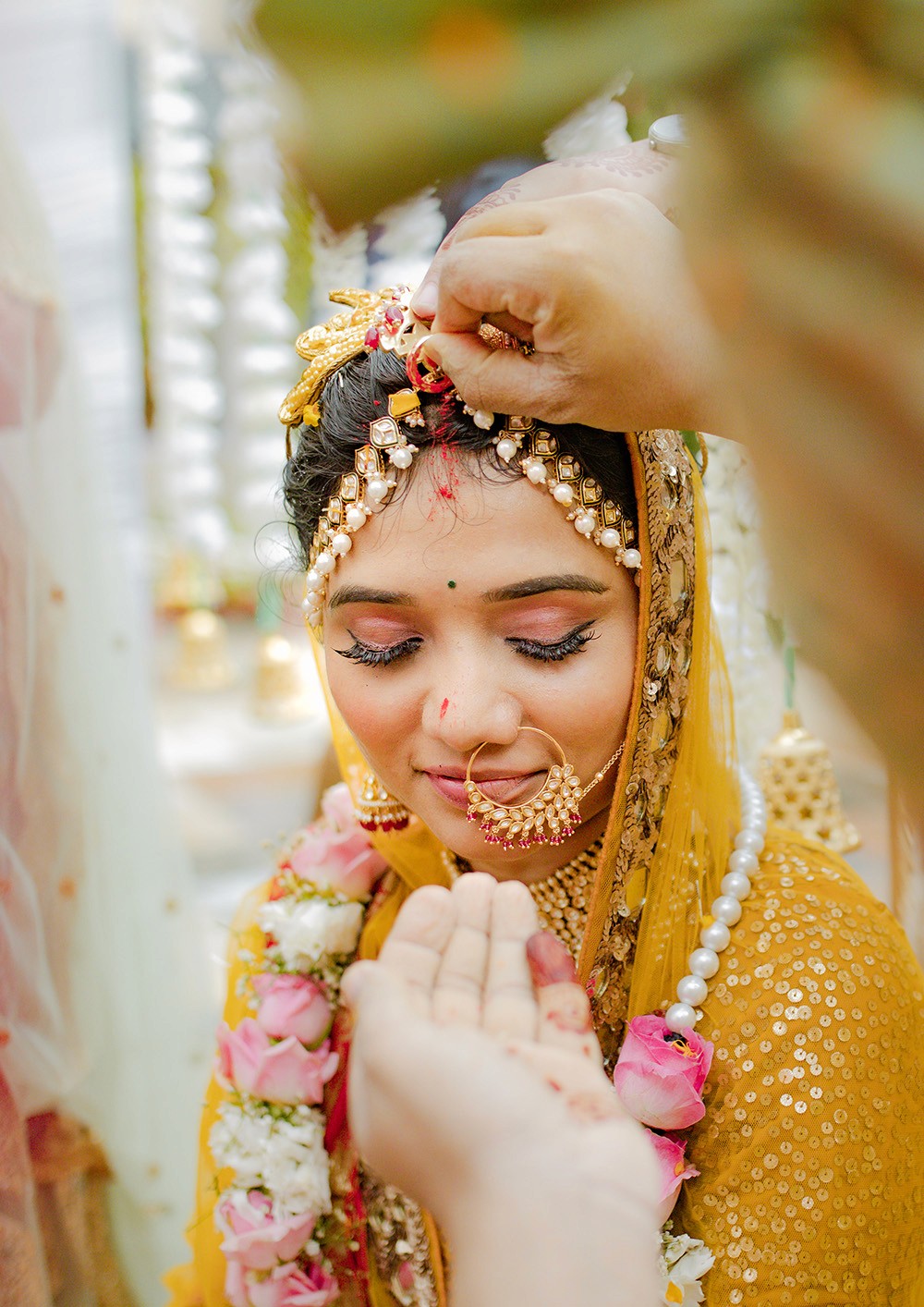 A man sits peacefully on a rocky mountain peak, gazing out at the expansive view of rolling hills and valleys bathed in soft, natural light.