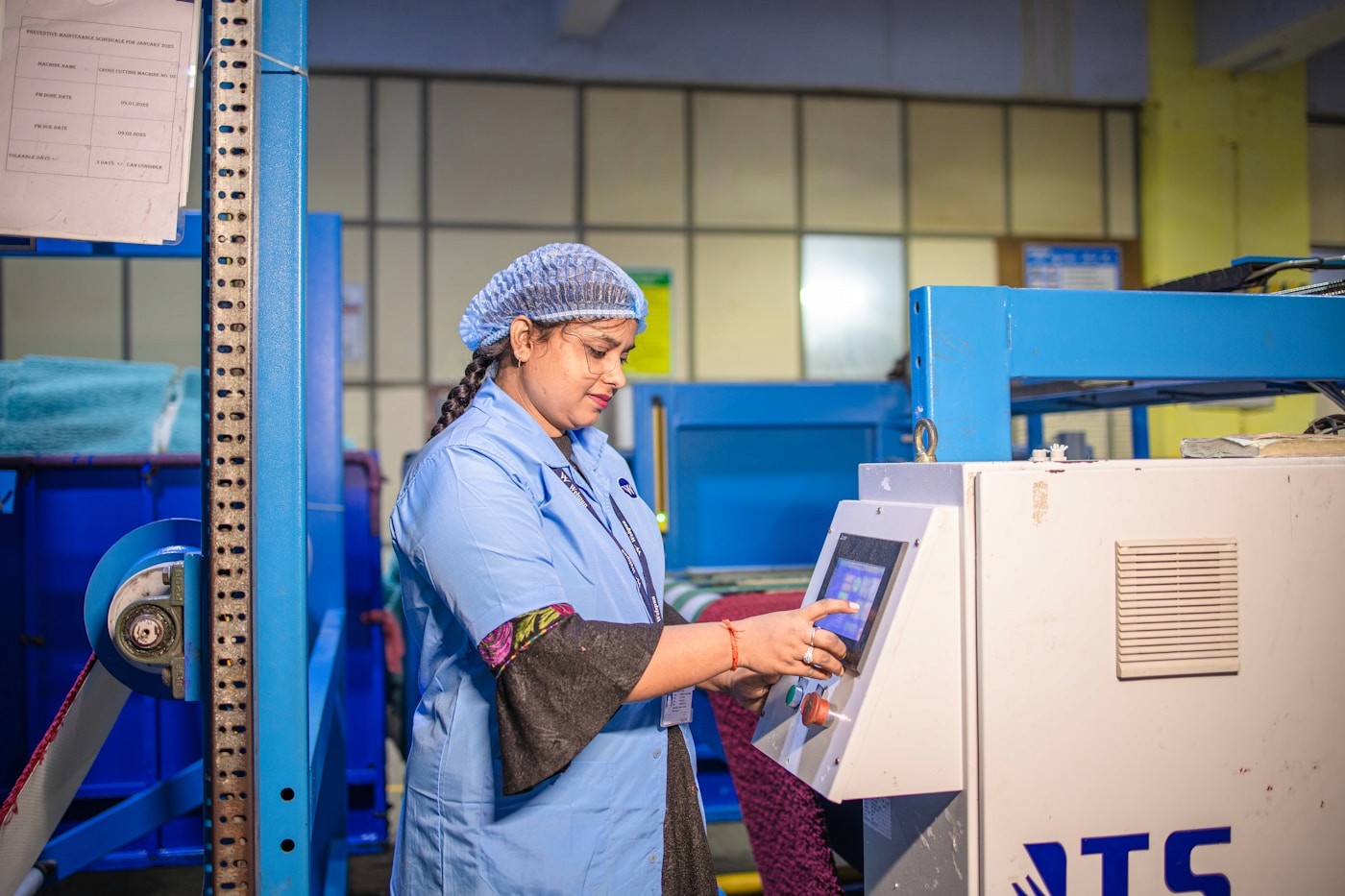 Indian factory worker operating a digital touchscreen control panel on a machine