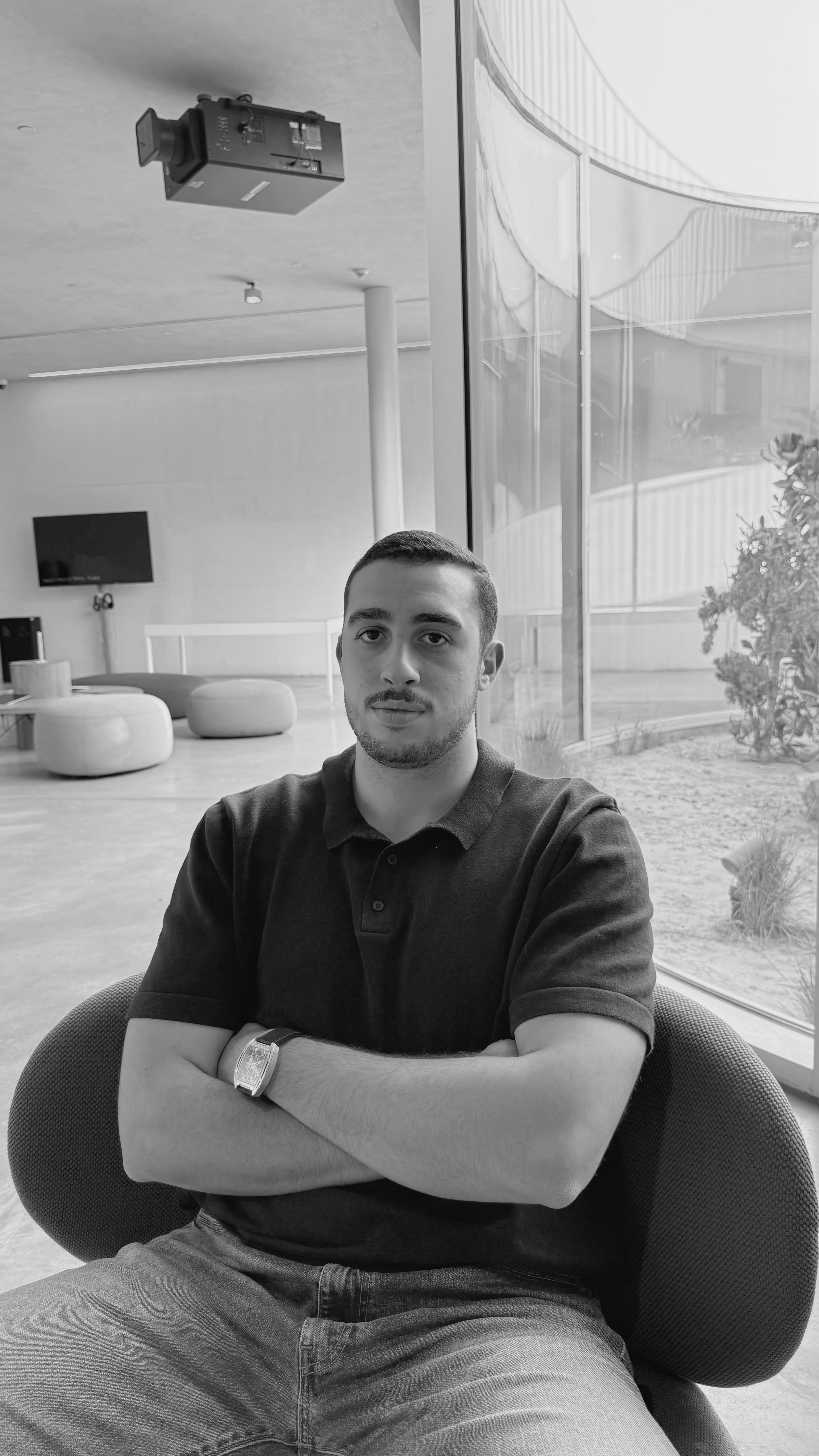 An ostrich is peeking at a man who is reading a newspaper.