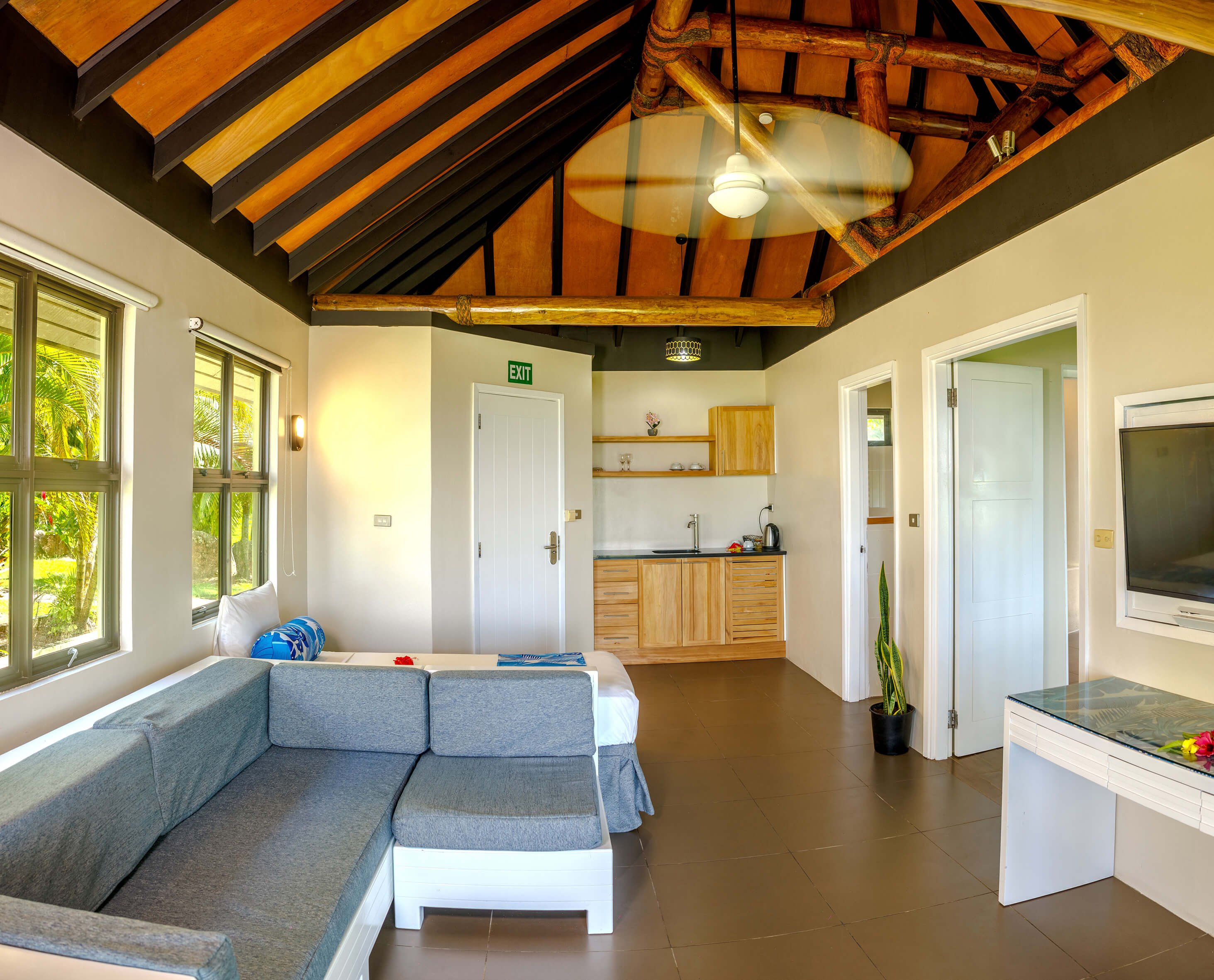 A clean bure at Uprising Beach Resort  Fiji with lounge and kitchenette desk and tv