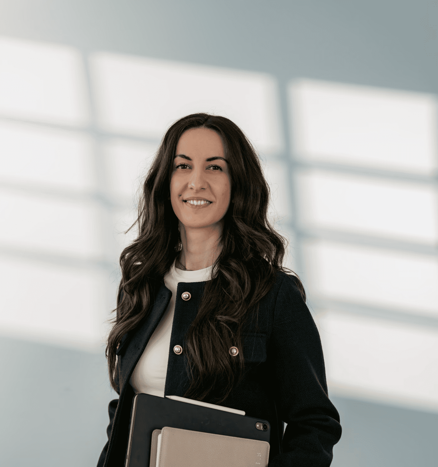 Frontalbild einer jungen Frau, die über die Schulte in die Kamera lächelt.