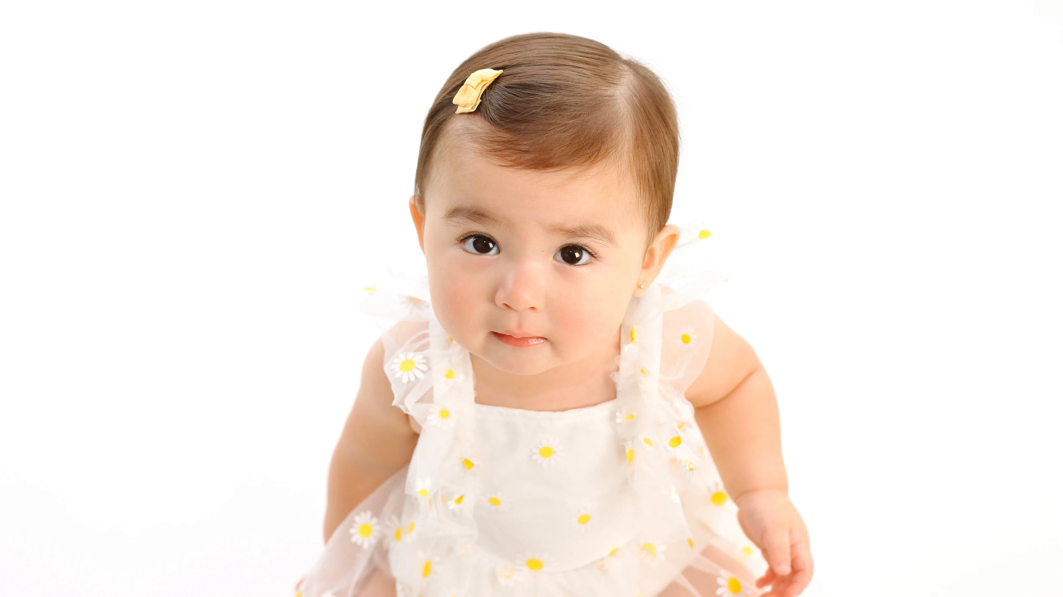 Primer plano de bebé con vestido blanco y flores amarillas