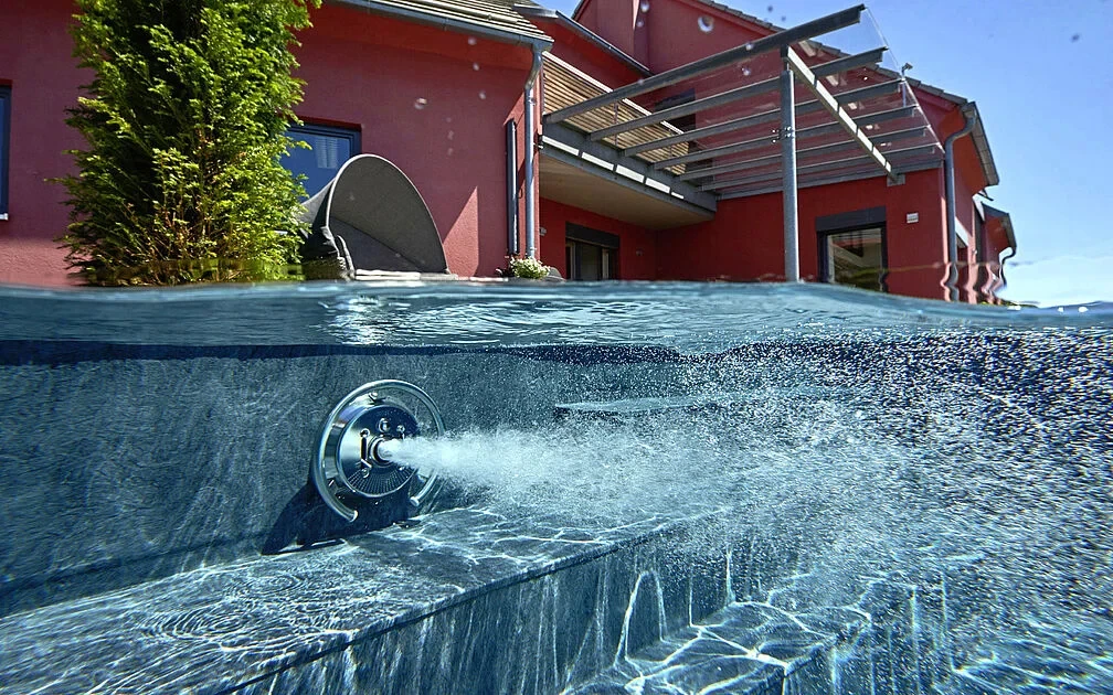 RENOLIT ALKORPLAN textured reinforced membrane pool lining with flush-mounted swim jet nozzle and slip-resistant entry steps.