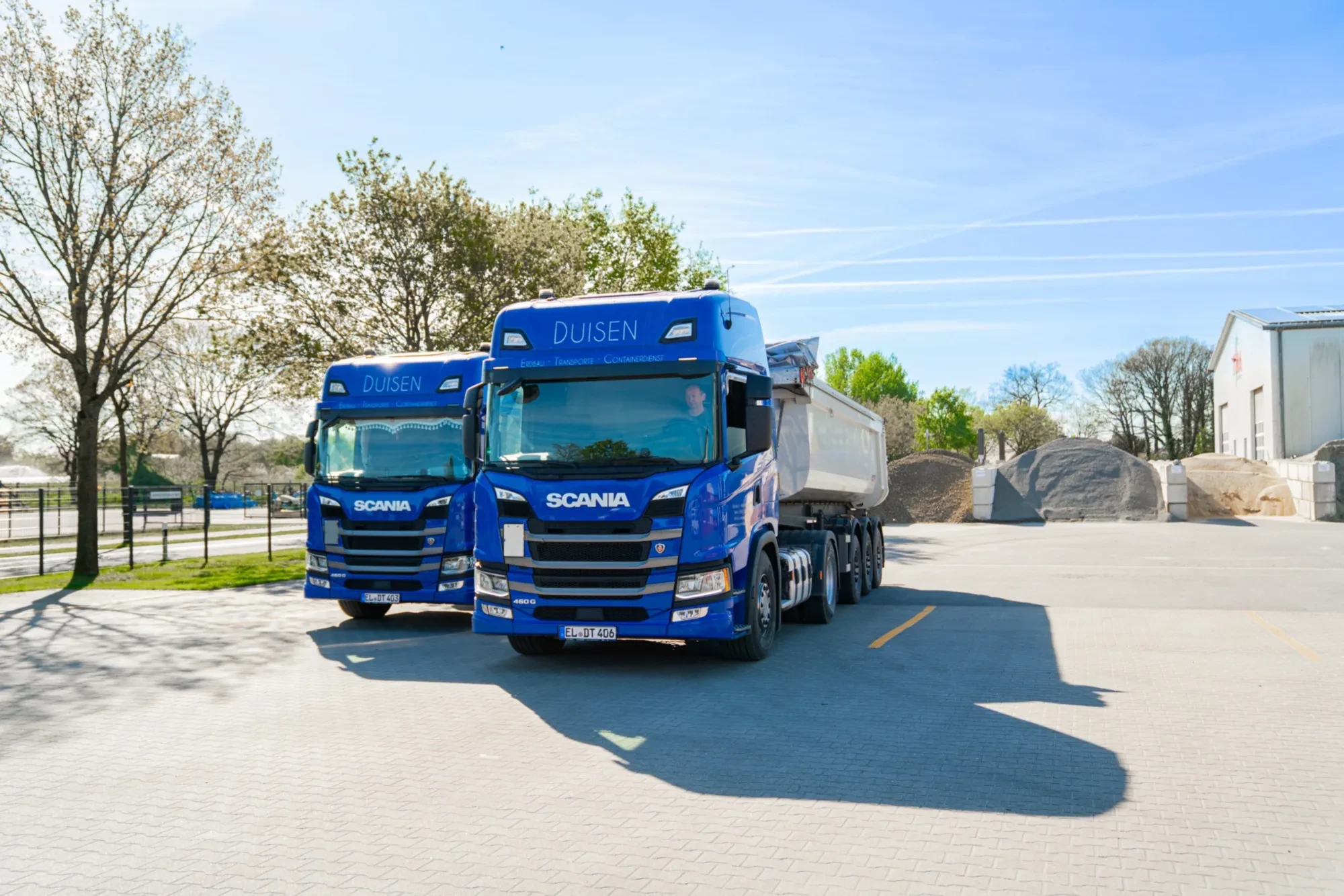 Zwei blaue Scania-Lkw „Duisen“ mit Kippmulde auf dem Betriebshof
