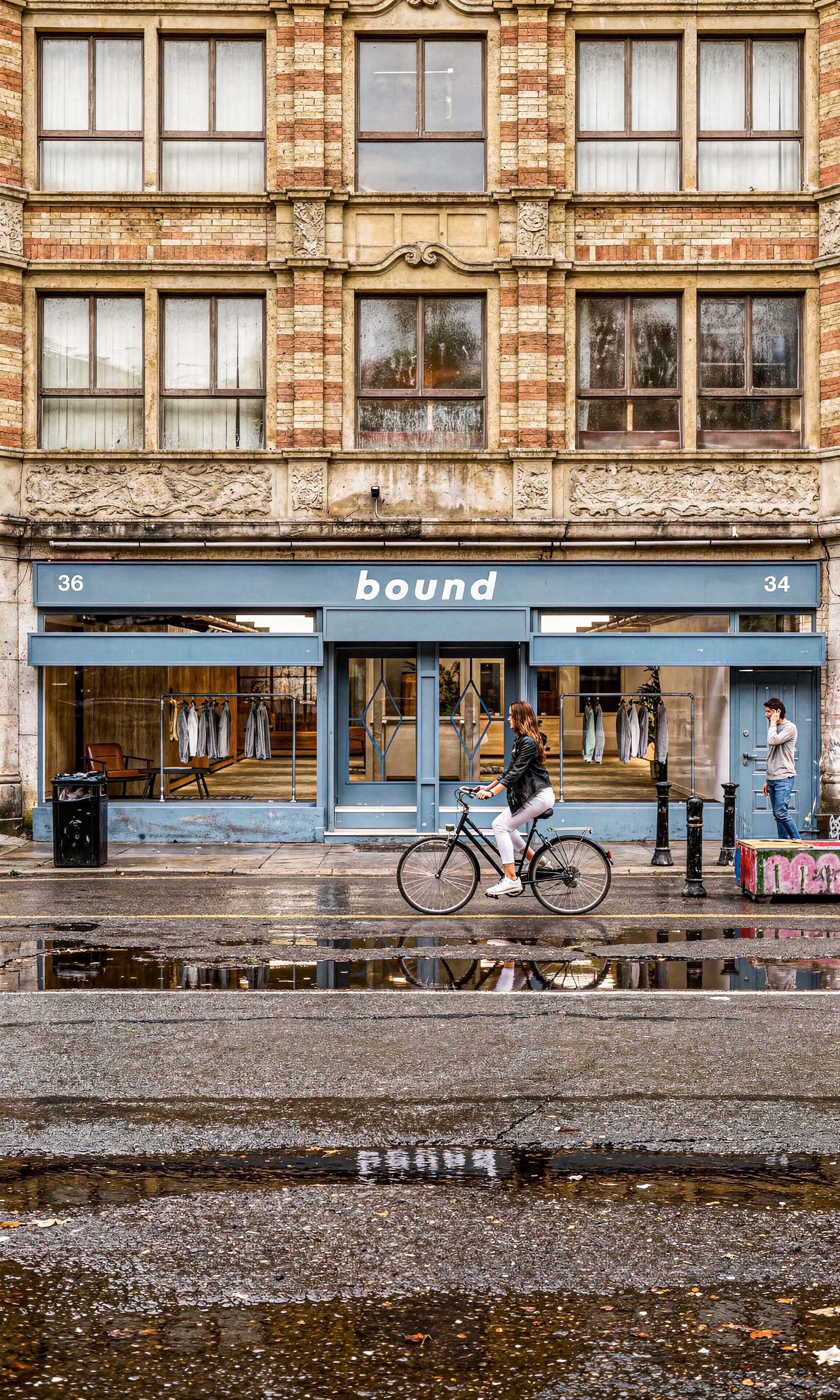 Photorealistic CGI architectural visualisation by James Lyons of PixelSpaces showing the proposed Bound clothing store on Thomas Street in Manchester's Northern Quarter, featuring retail storefront branding, heritage architecture, street-level activity and reflections within an urban fashion retail environment