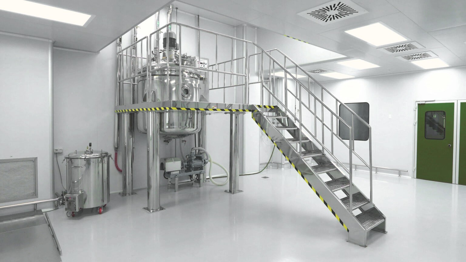Clean industrial environment with access stairs to stainless steel equipment, used in manufacturing or research processes.