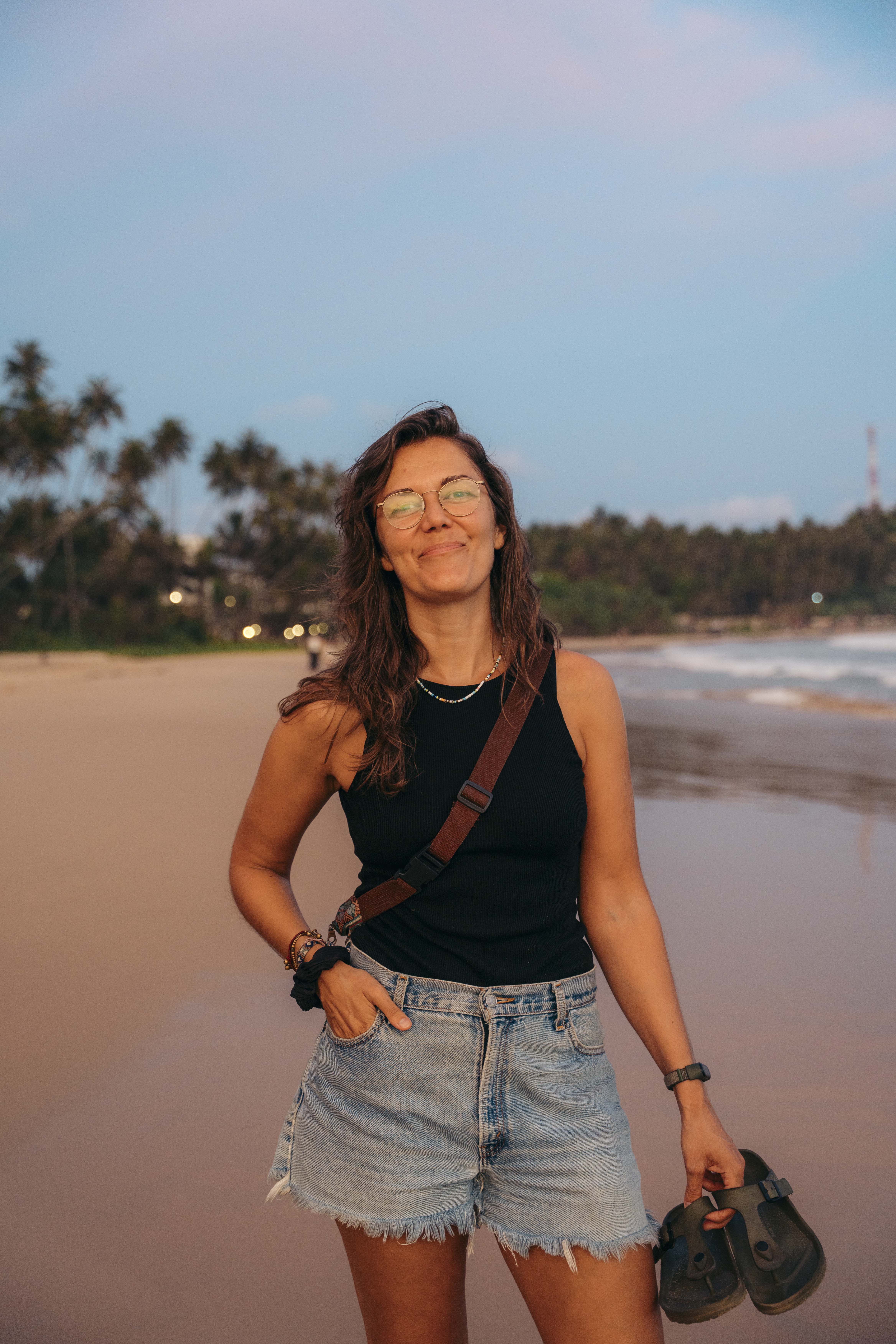 Eva walking along the beach at sunset during her travels.