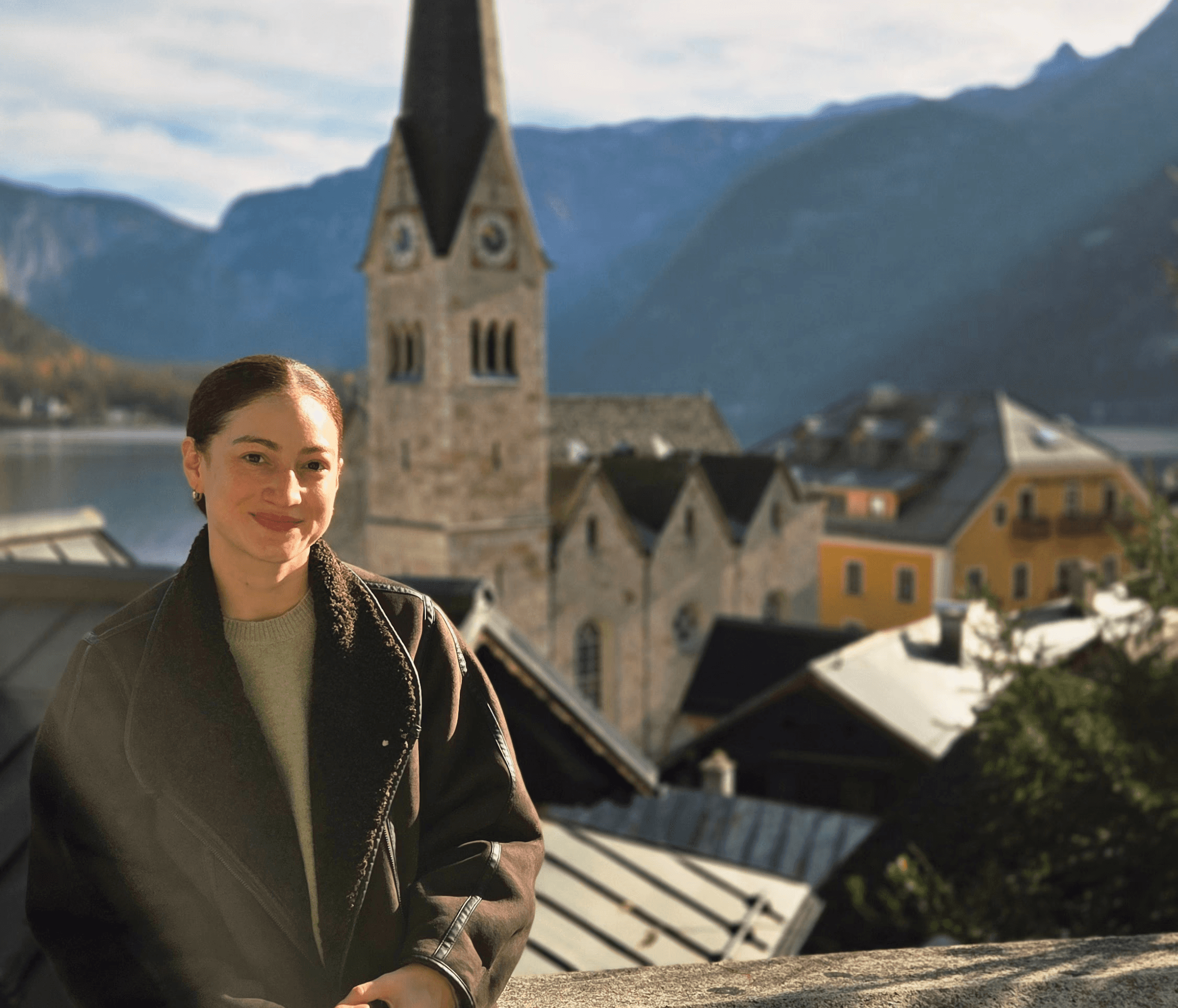 A smiling portrait of illustrator Mel Montoya outdoors with a city, lake, and mountains in the background.