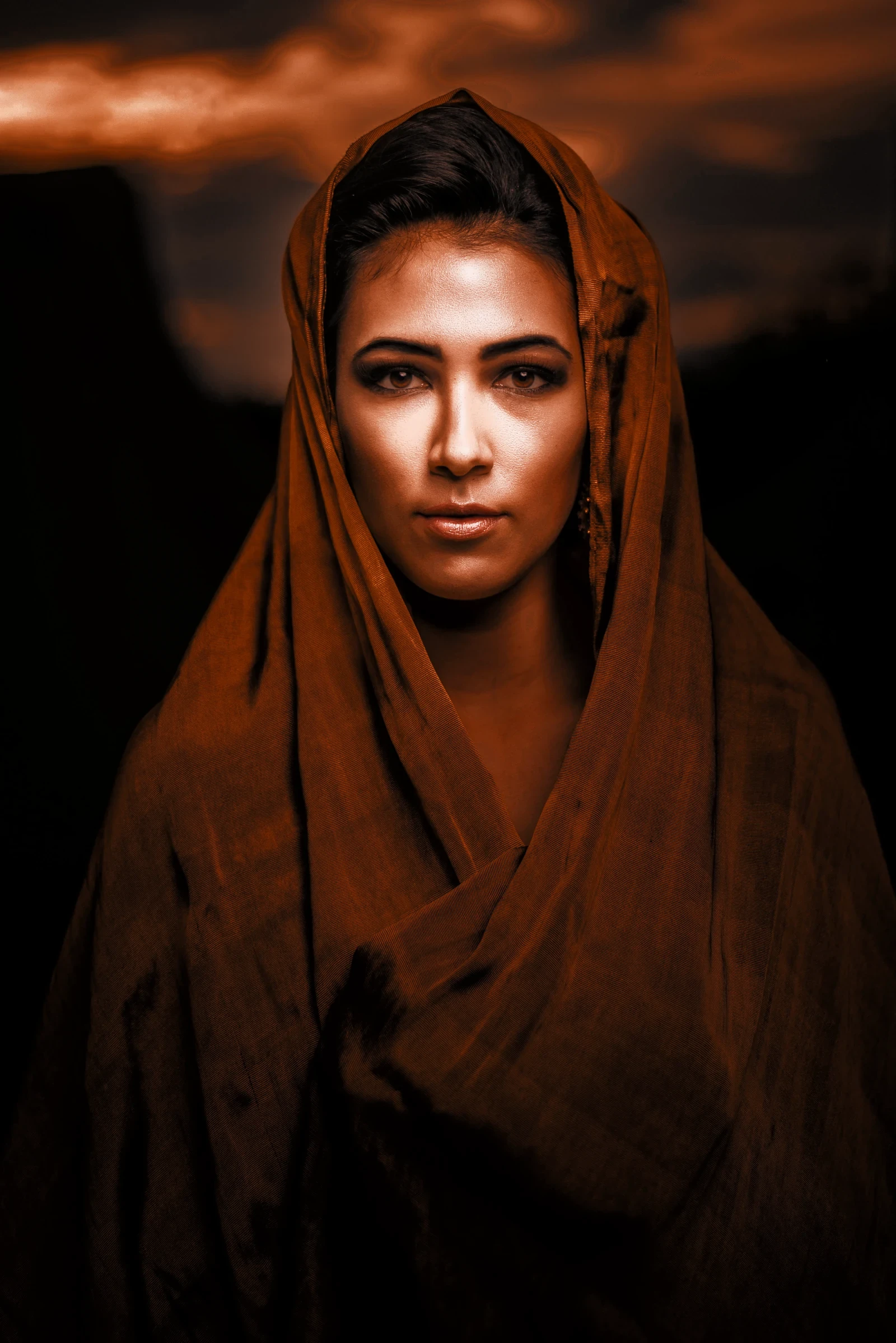 A woman in a brown headscarf looks into the camera
