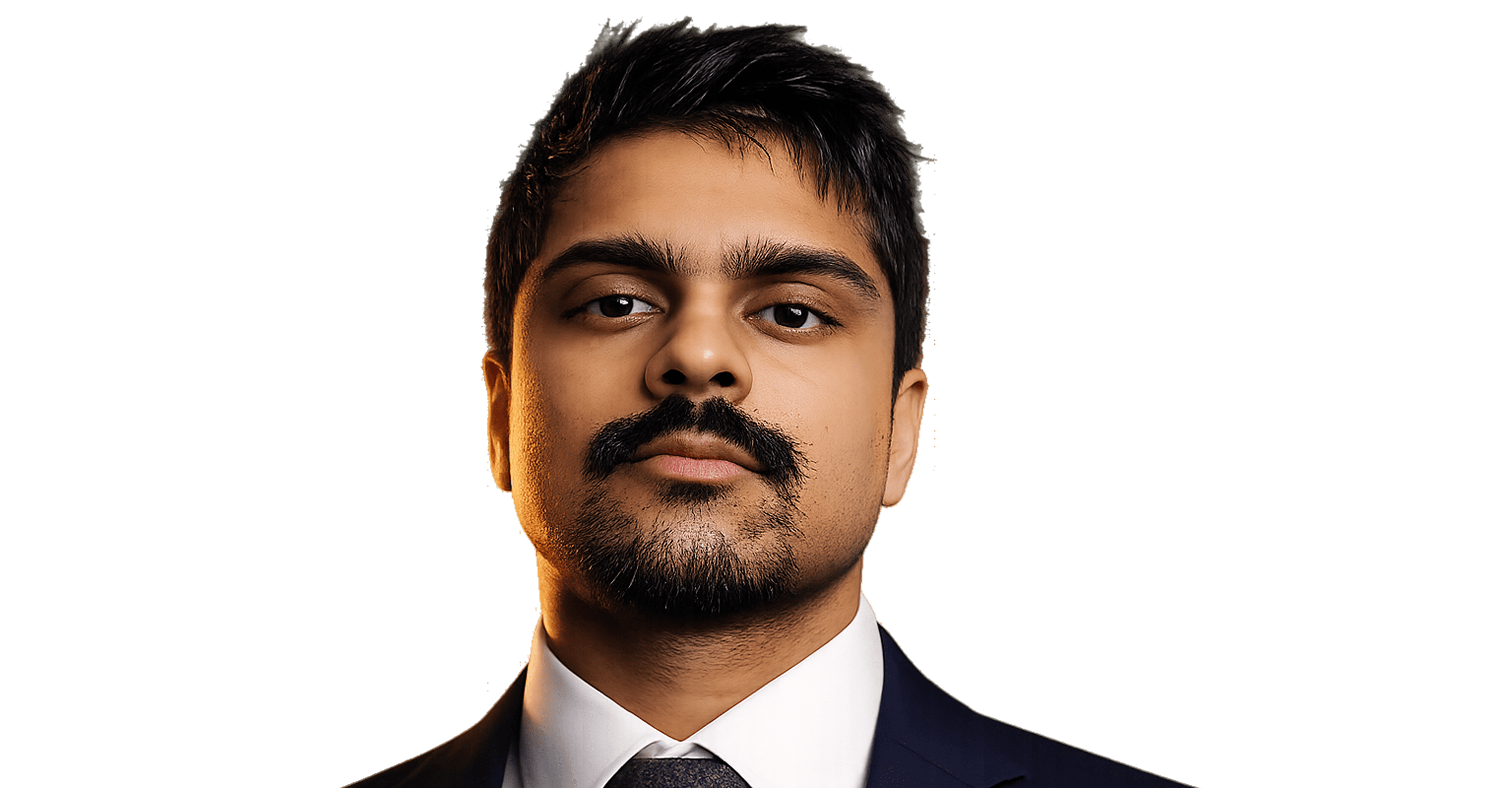 Portrait of a man in a dark suit and tie with short black hair, mustache, and beard, looking confidently at the camera against a black background.