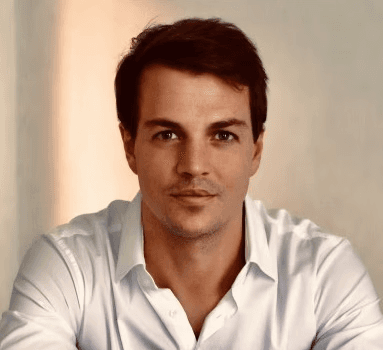 Portrait of a person in a pink sweater against a light background
