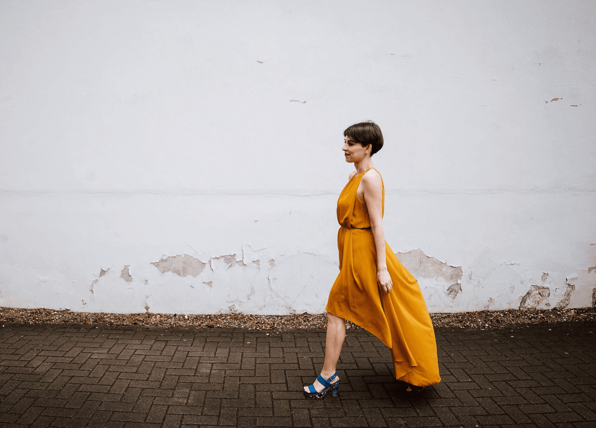 Francesca Introvaia walking outdoors in a flowing yellow dress.
