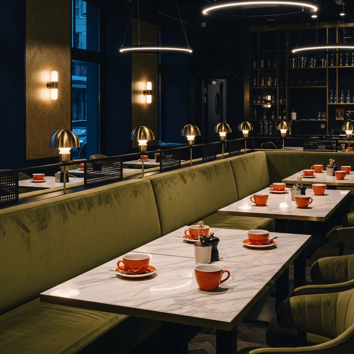     Long communal dining table beneath dramatic architectural lighting.