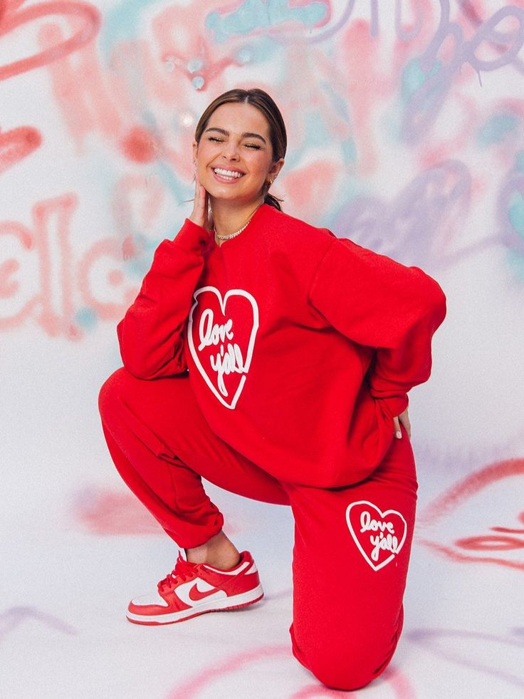 A person in a red outfit poses confidently in front of a colorful background.