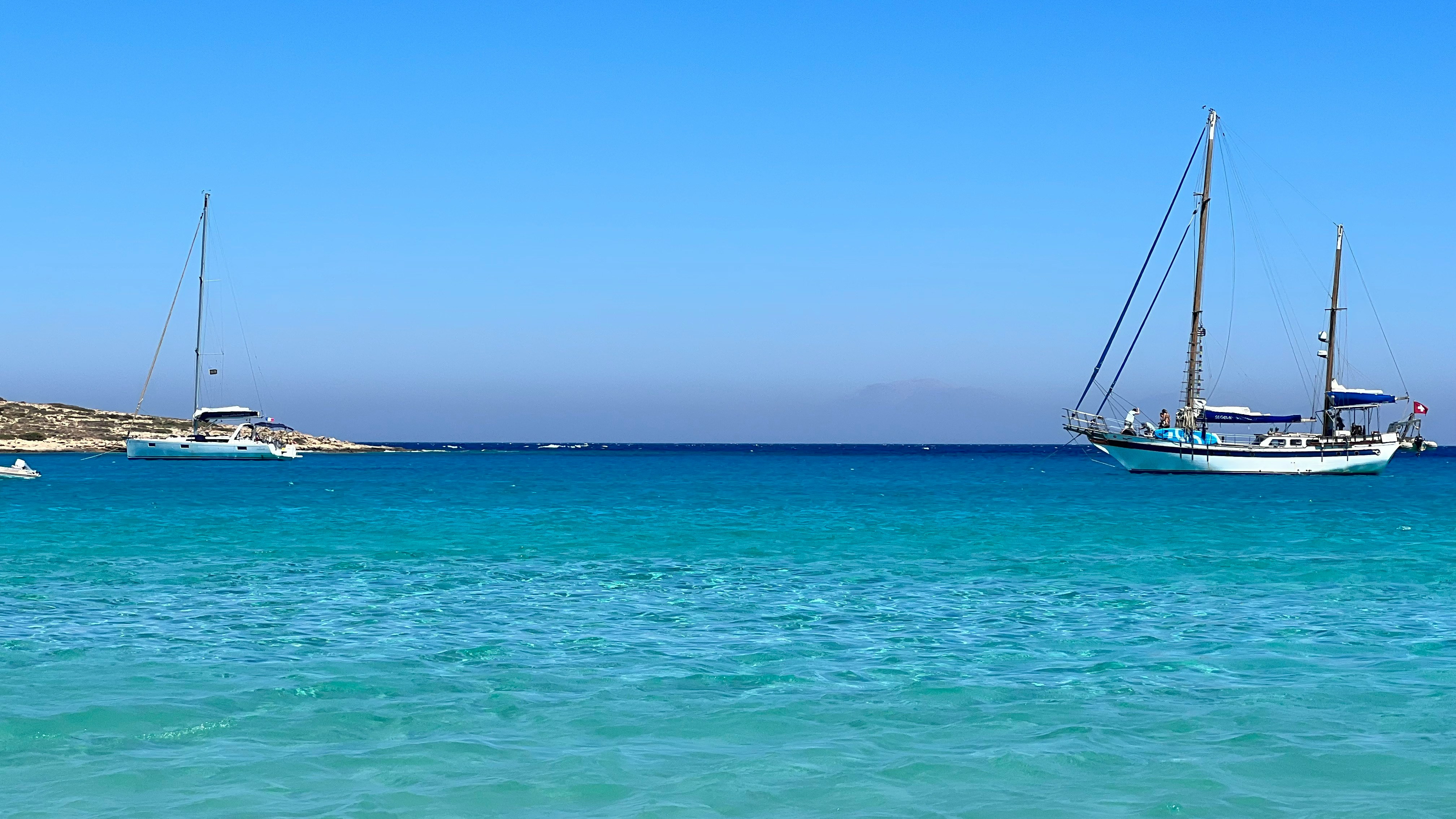 Boats anchored in clear turquoise water in the Small Cyclades