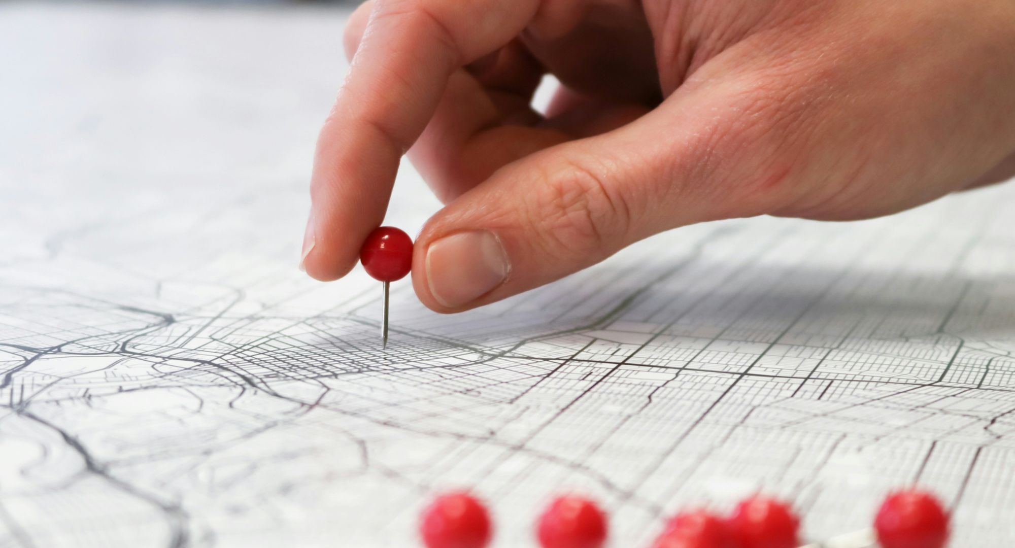 plane detalhe da mão de uma pessoa colocando um alfinete de cabeça vermelha em algum lugar de um mapa
