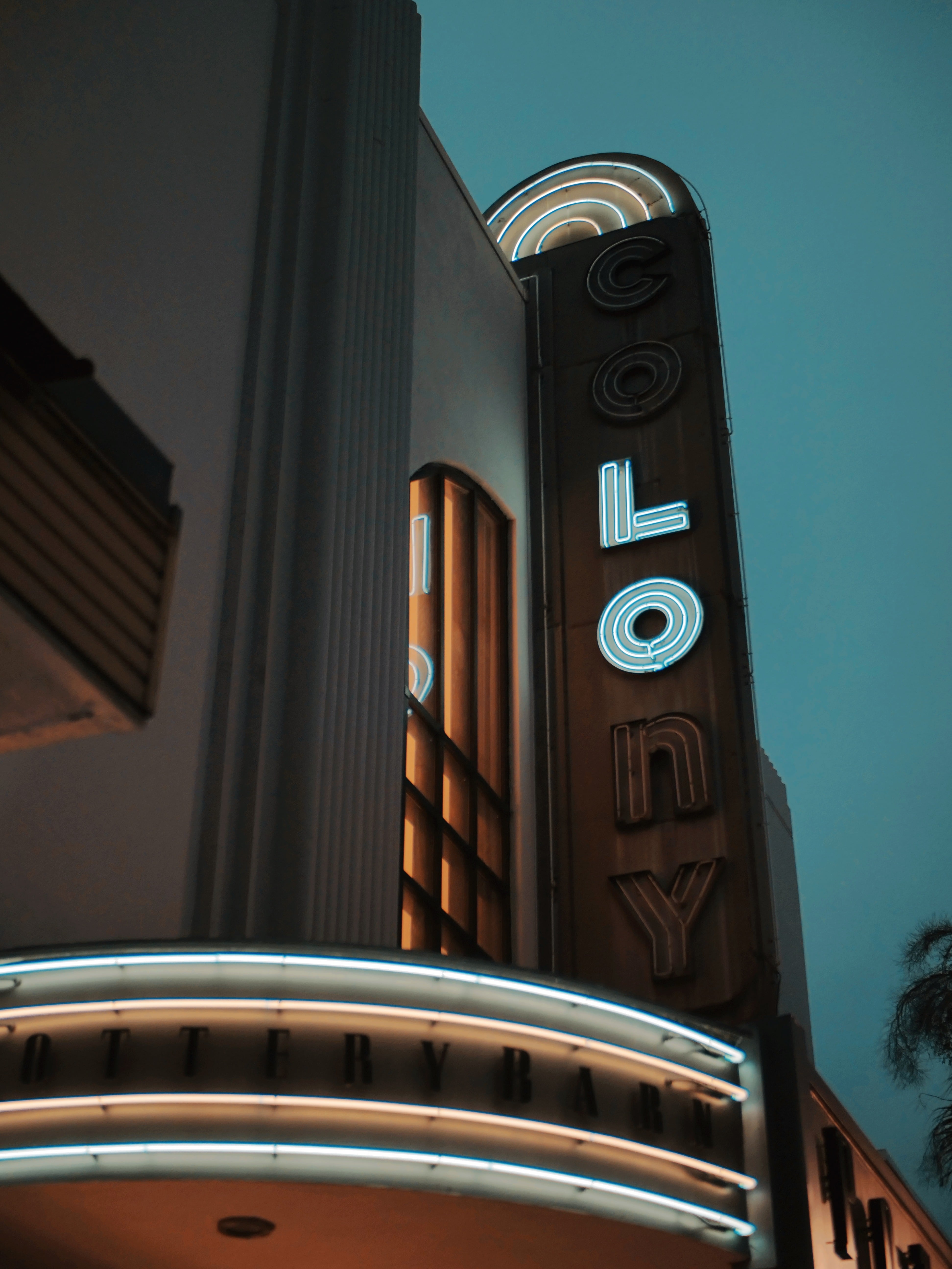 Neon Colony theater sign against a teal sky
