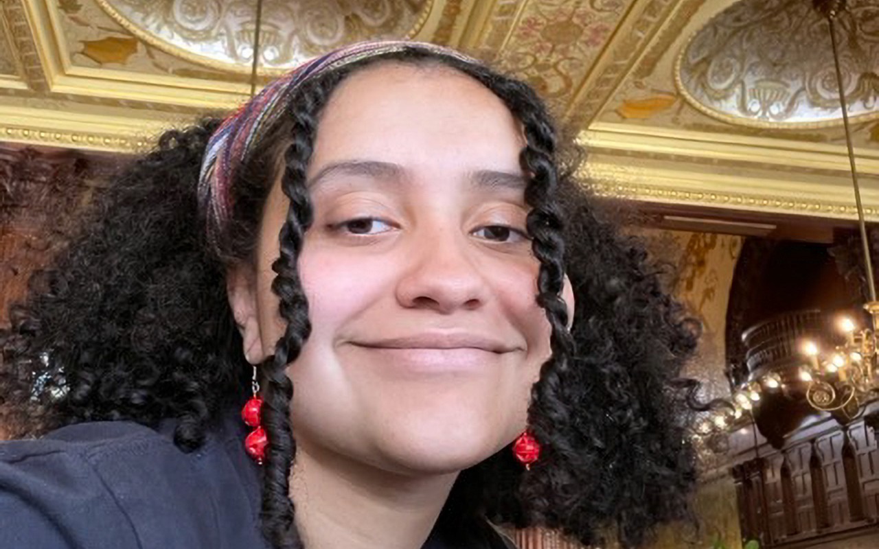 woman with curly hair, smiling, in an ornate room