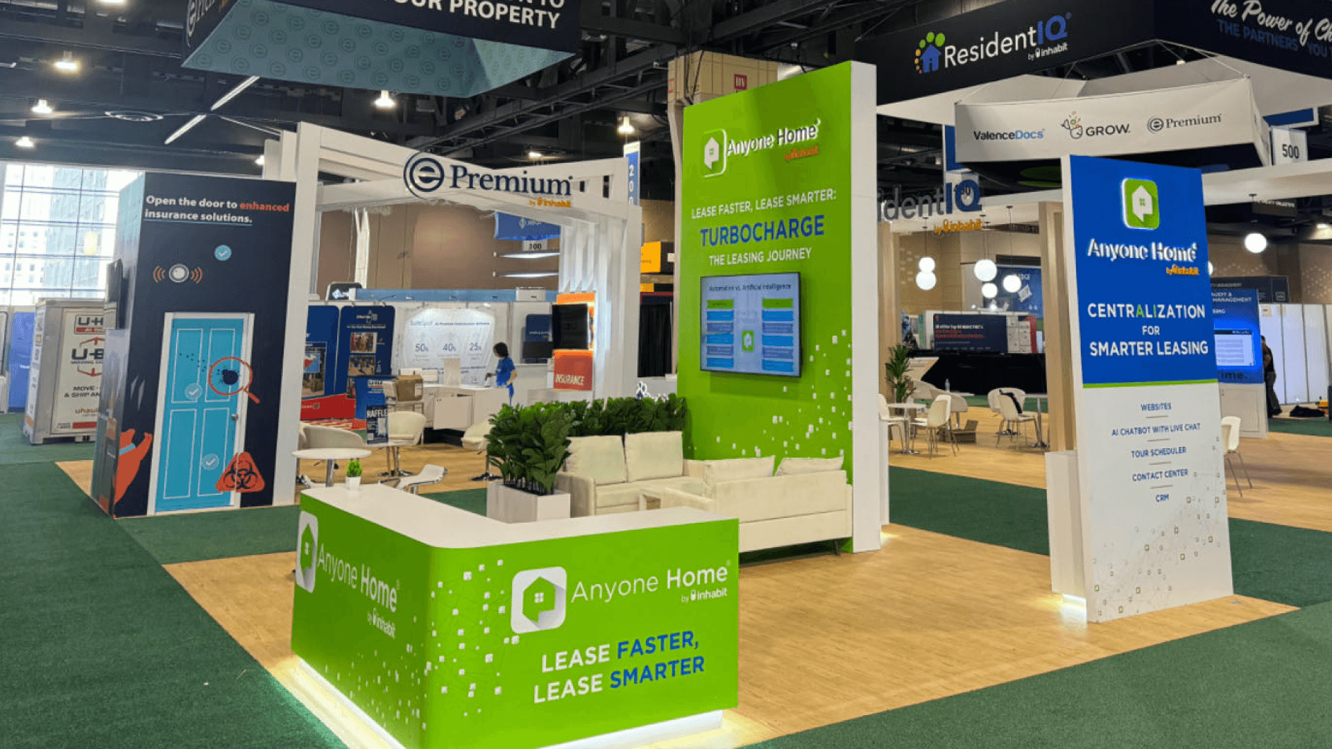 Anyone Home NAA 2024 20x20 professional service booth with lounge seating, green demo wall, front reception counter, and leasing technology presentation area.