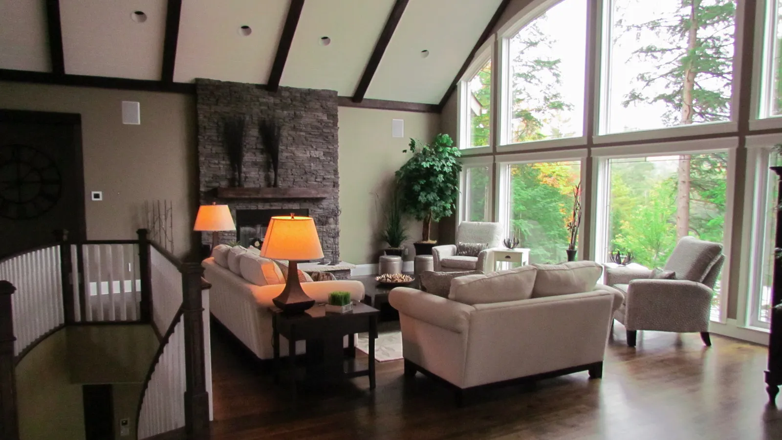 interior living room of high end cottage looking out the large floor to ceiling windows towards the forest with high ceilings and luxury high end finishes.