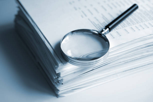 Close-up of financial paperwork and a magnifying glass, representing careful review of complex financial products.