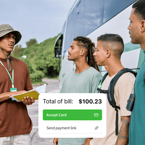 Tour guide holding a map and talking to three young men with backpacks near a tour bus.