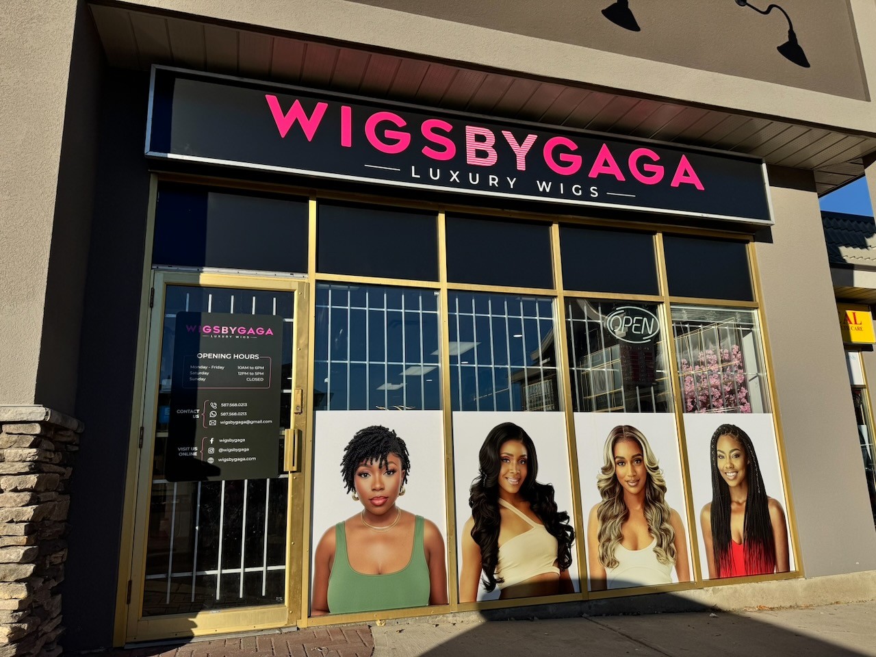 A professional storefront display in Calgary featuring a pink and white backlit fascia sign for Wigs by Gaga and custom vinyl window portraits of models with various hair styles.