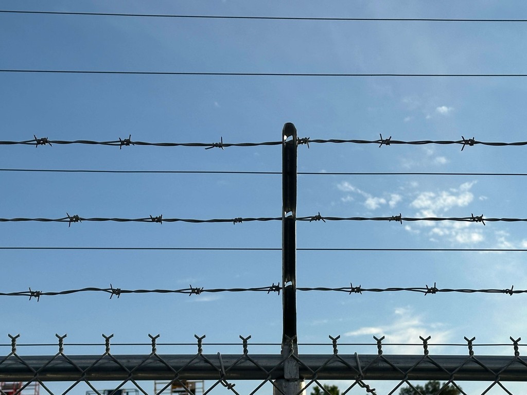 This picture shows a close up of a security fence with razor wire or barbed wire at the top that we can install around properties.  We also run security fencing from our welding and fabrication shop in Henderson, Texas.