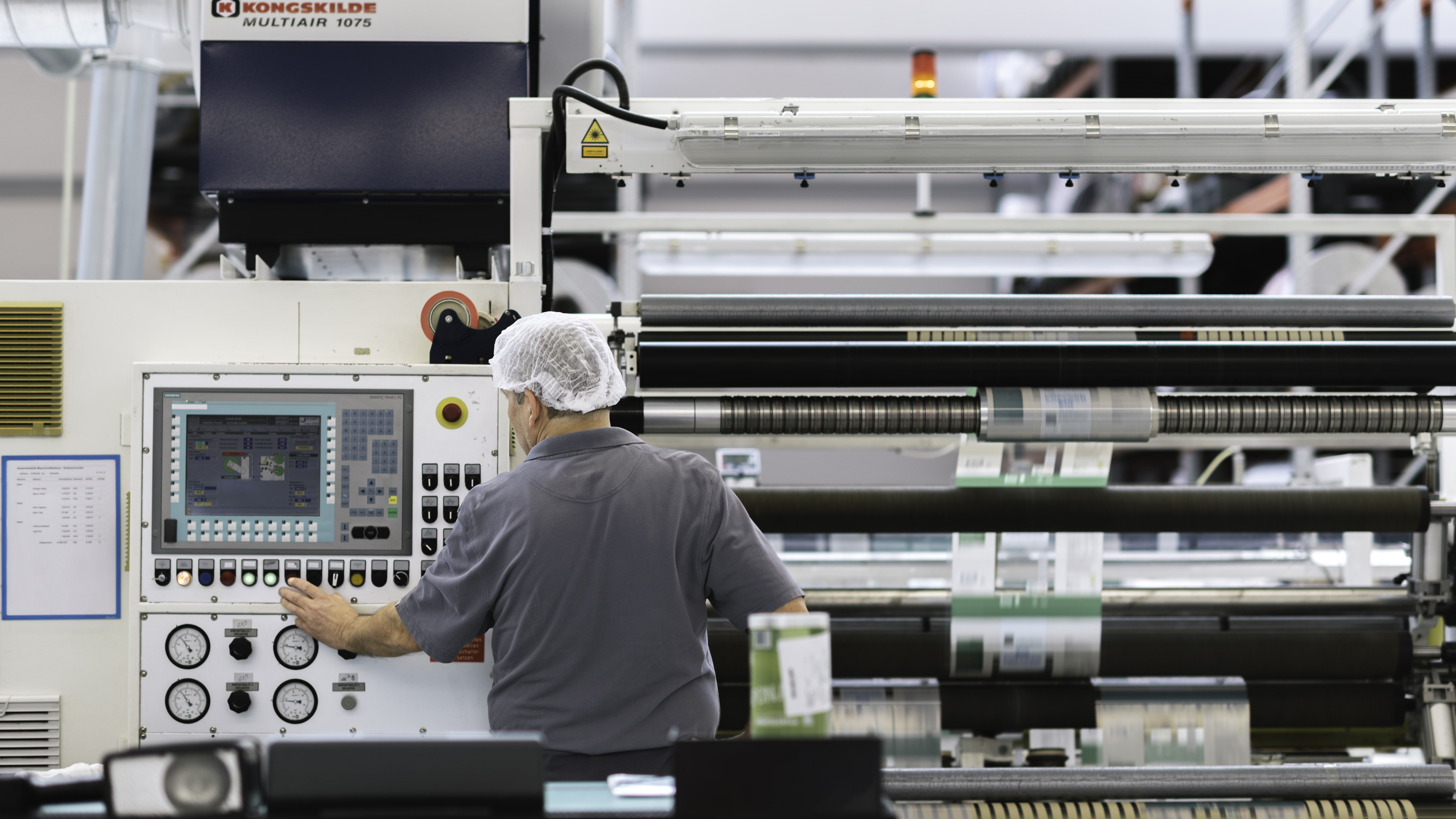 Scheyer technician operating a large printing machine, ensuring precise packaging production.