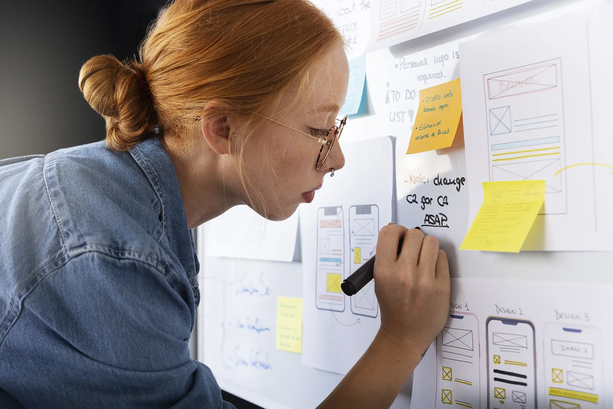 Designer skizziert Wireframes der ULTIDO-Web-App auf einem Whiteboard voller Haftnotizen