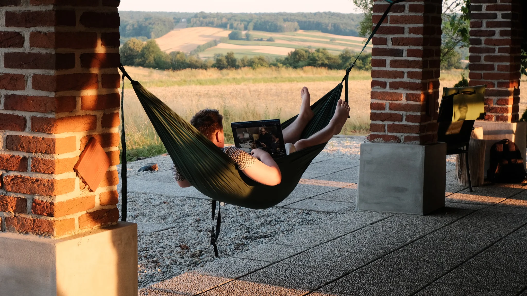 Person liegt mit dem Laptop in einer Hängematte