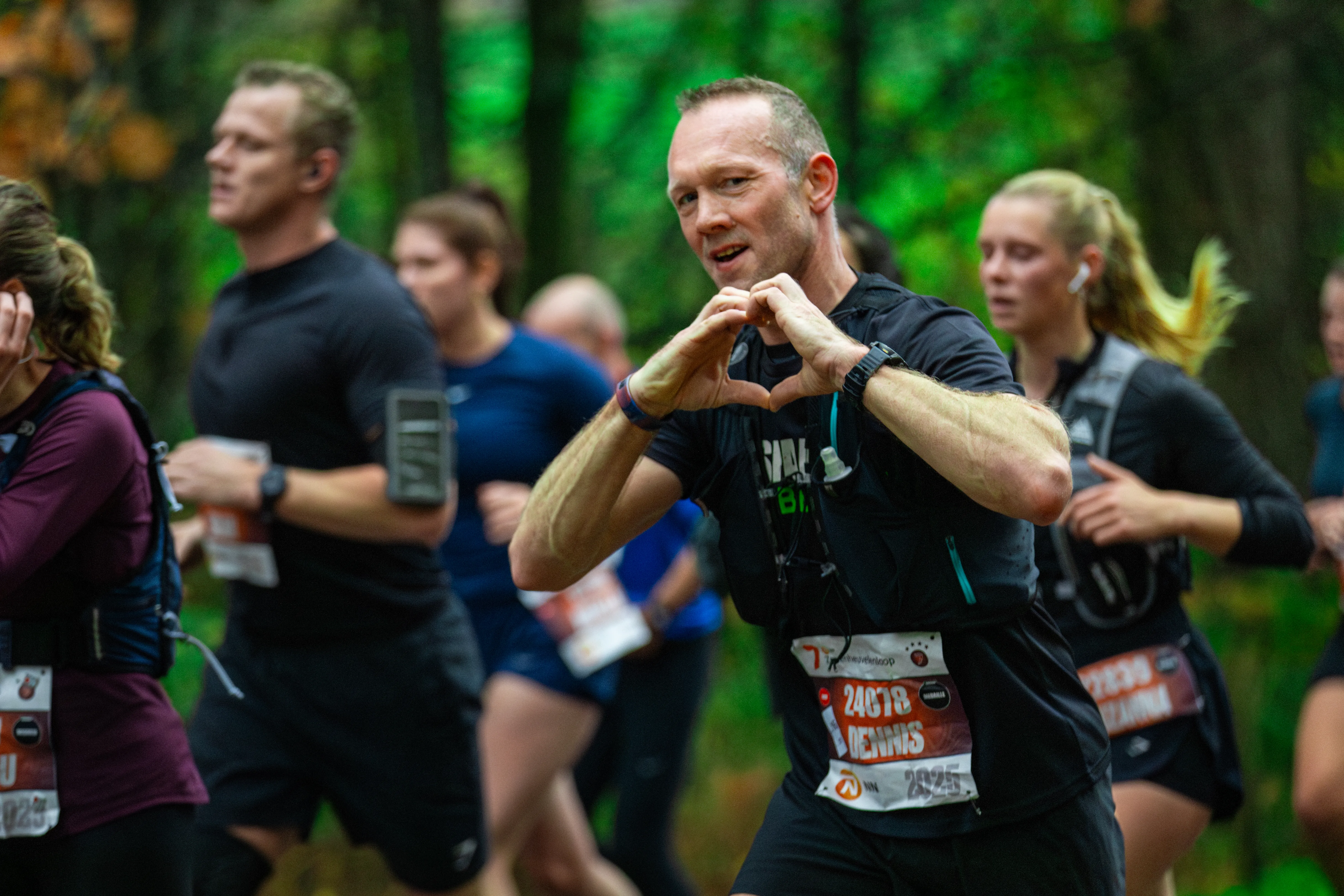 een deelnemer van de zevenheuvelenloop 2025 maakt hart-gebaar met handen naar camera