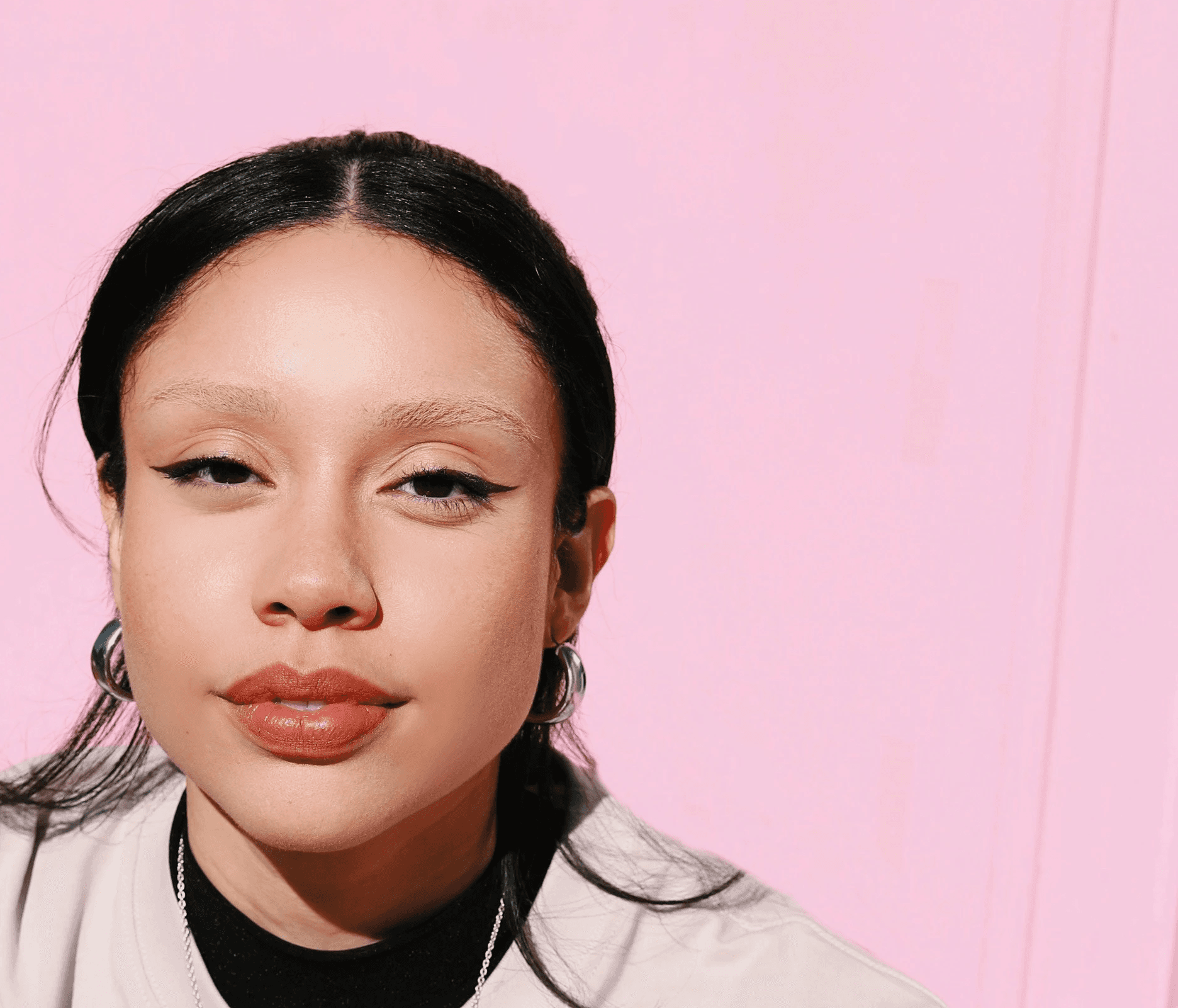 a woman sitting at a table in front of a pink wall
