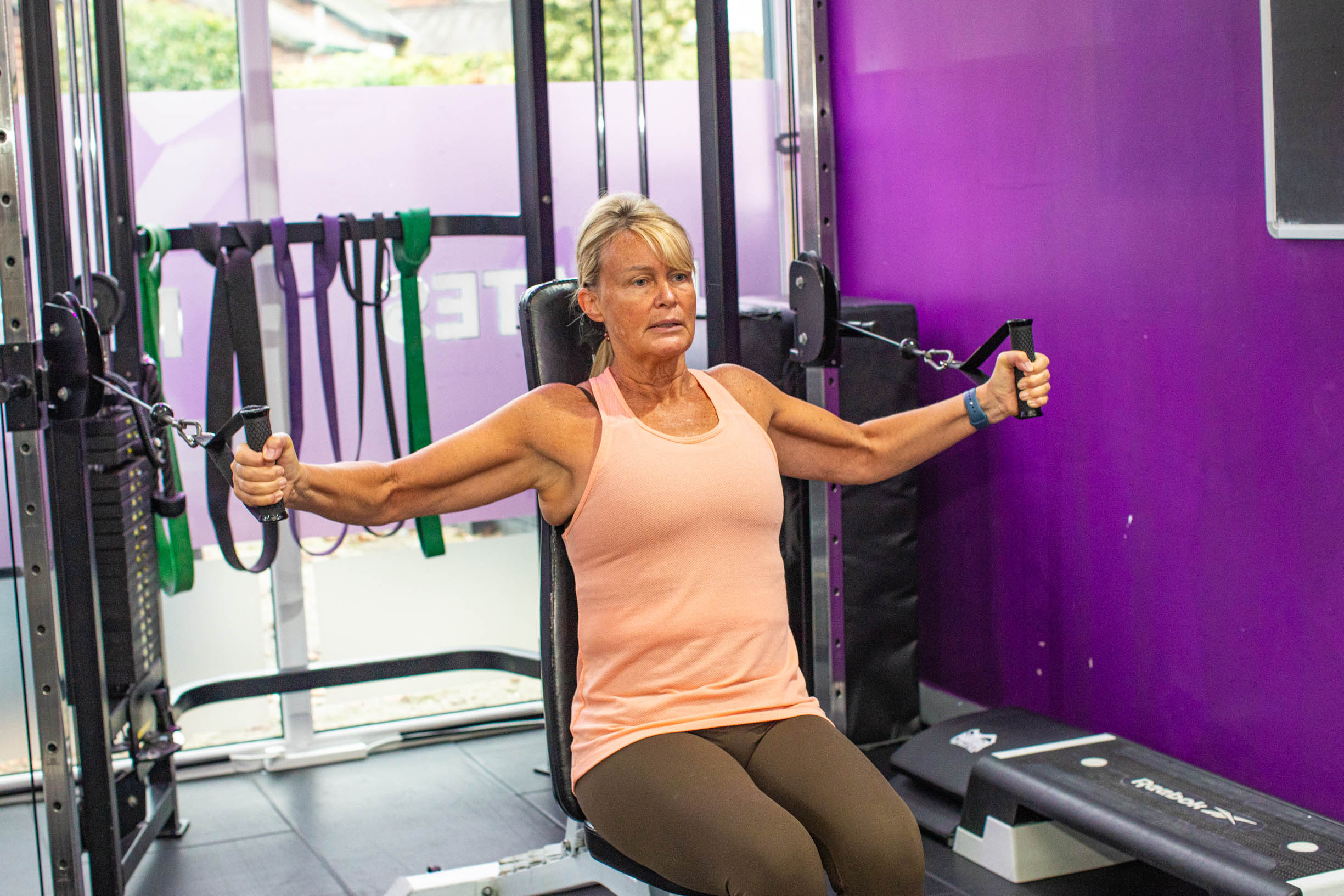 A woman performing a pull-up on a machine, highlighting her dedication to fitness and the health benefits of ginger by Alchemy