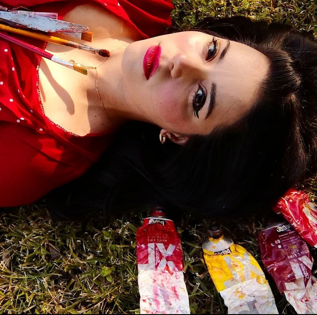 Close-up of two smiling friends with freckles, bright makeup, on a light blue background—joyful, inclusive brand portrait.