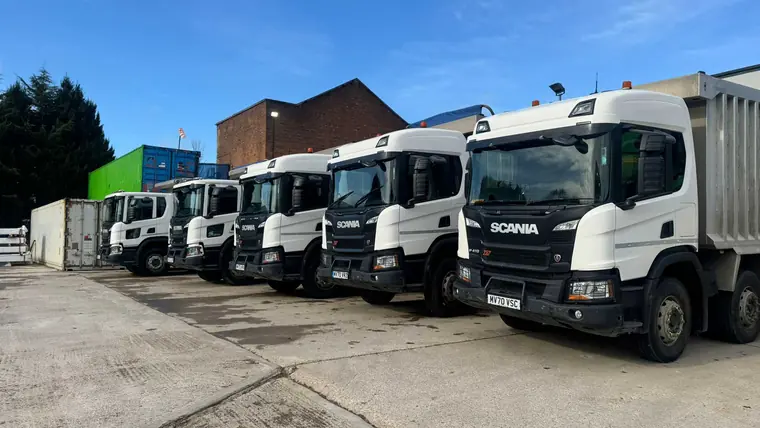 Fleet of heavy-duty haulage trucks supporting bulk earthworks and large-scale material transport on a commercial construction project.vators and dump trucks carrying out bulk earthworks and drainage installation on a large-scale civil engineering infrastructure project.