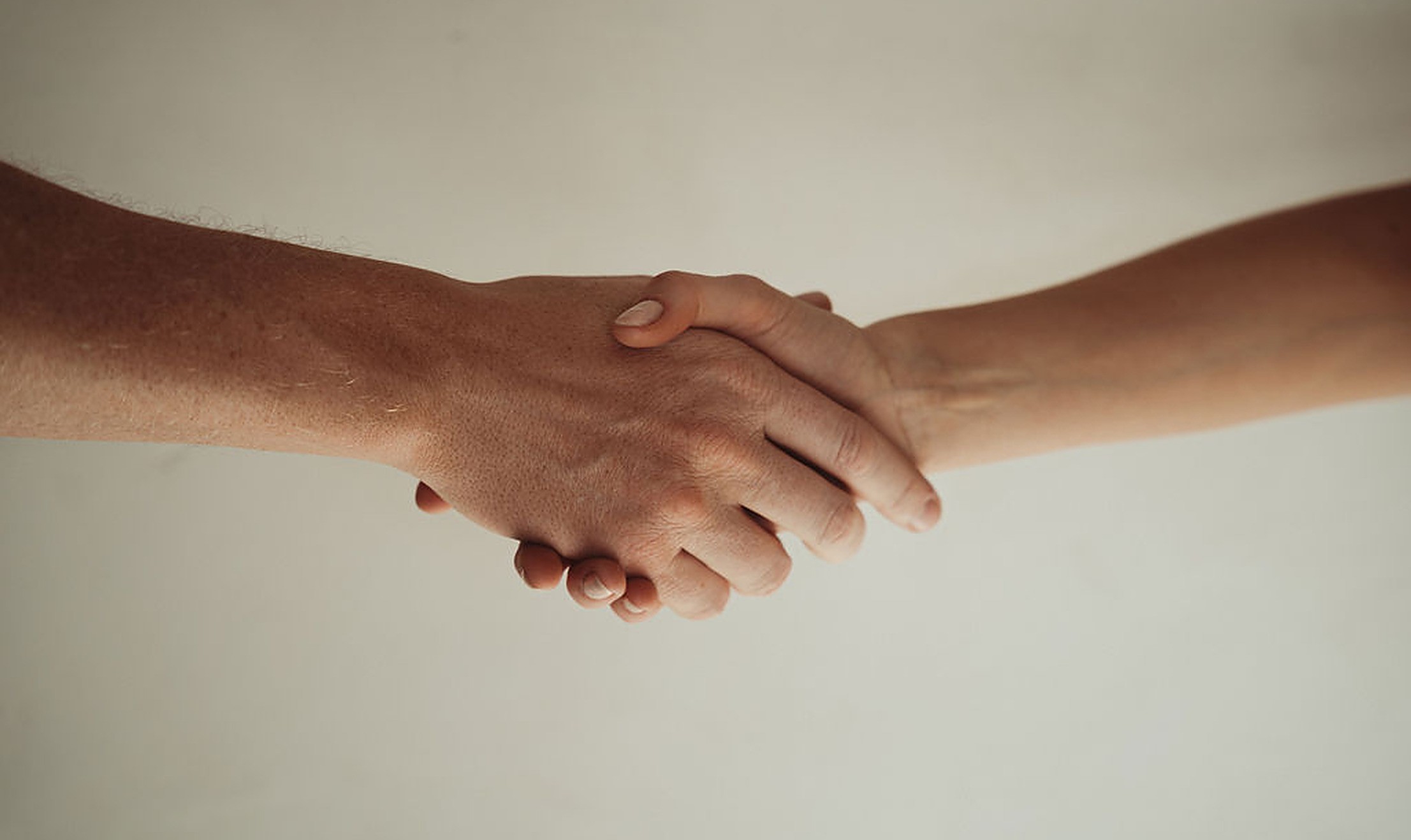 Two hands reaching across to clasp each other in soft light, a hopeful image of reconnecting and working to overcome intimacy issues together.