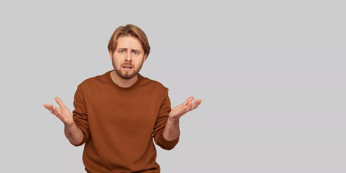 A man stands while two people sit at a table in an office setting, smiling and engaged in conversation. The mood is friendly and collaborative.