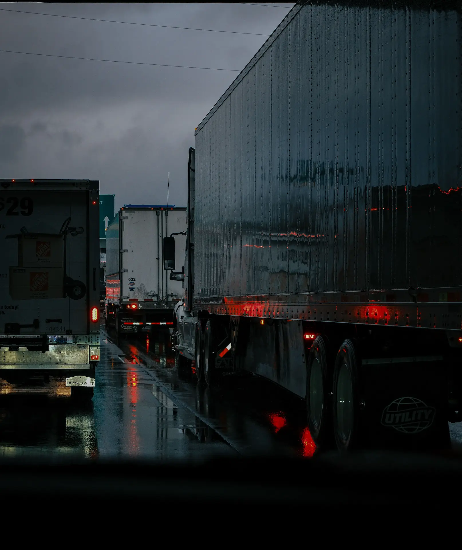 Freight trucks driving in traffic on a highway at dusk