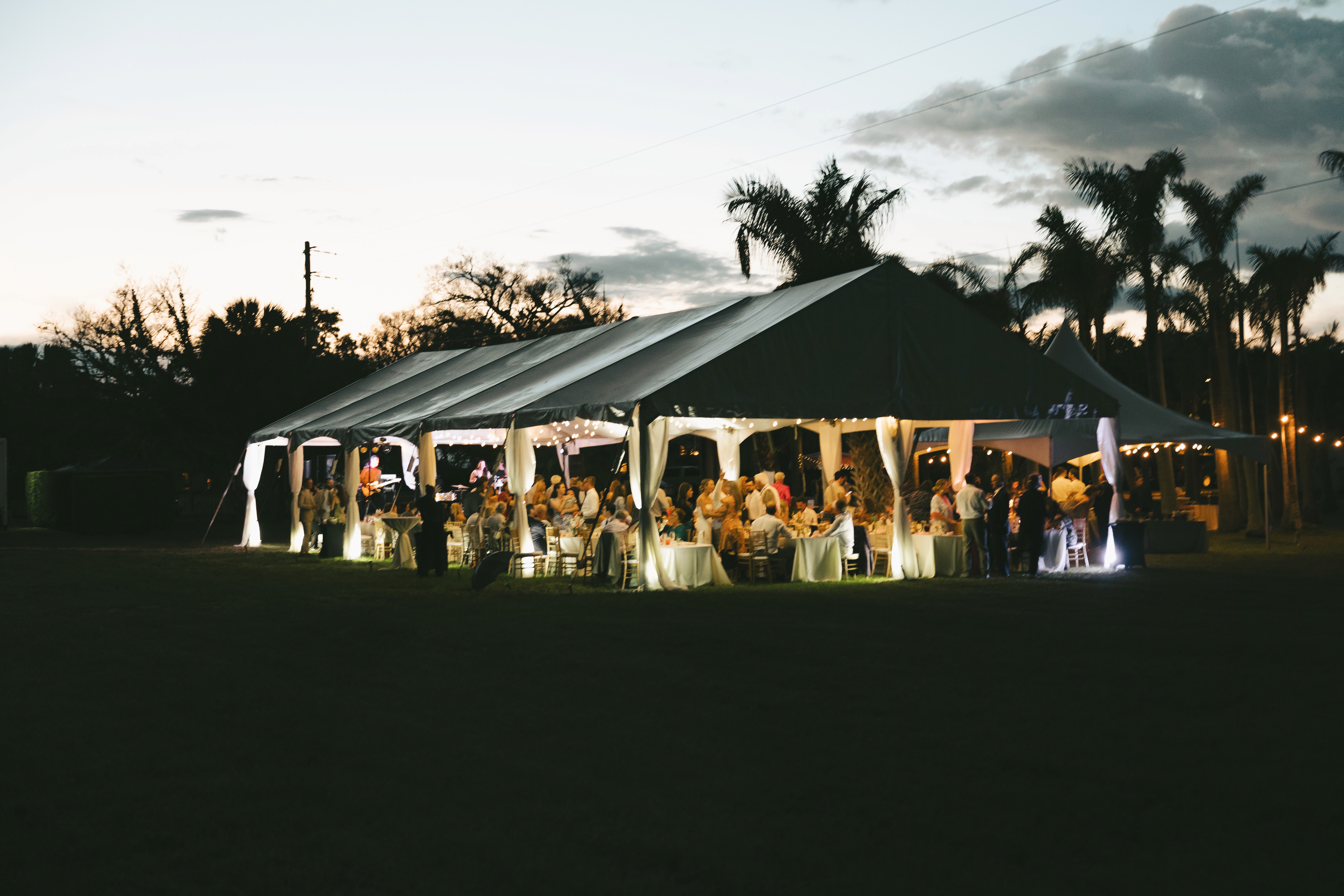     Palm Beach wedding photographer captures a tented outdoor wedding reception glowing at dusk.