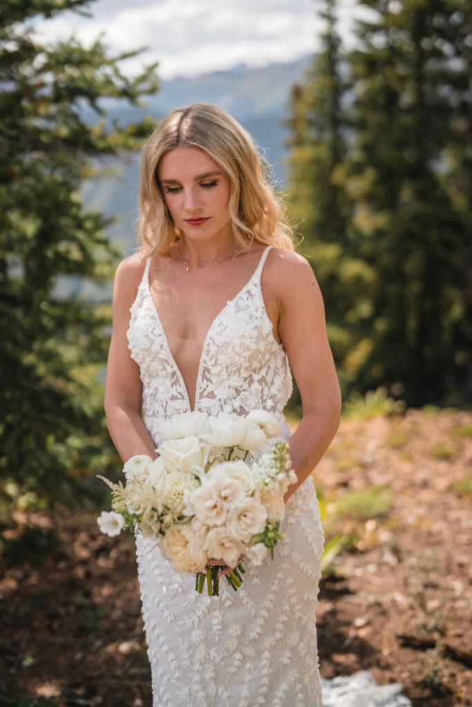 Bride holding a white bouquet on a mountainside