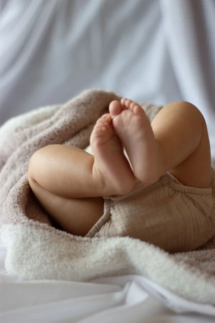 Close-up of sleeping baby legs tucked into a soft blanket