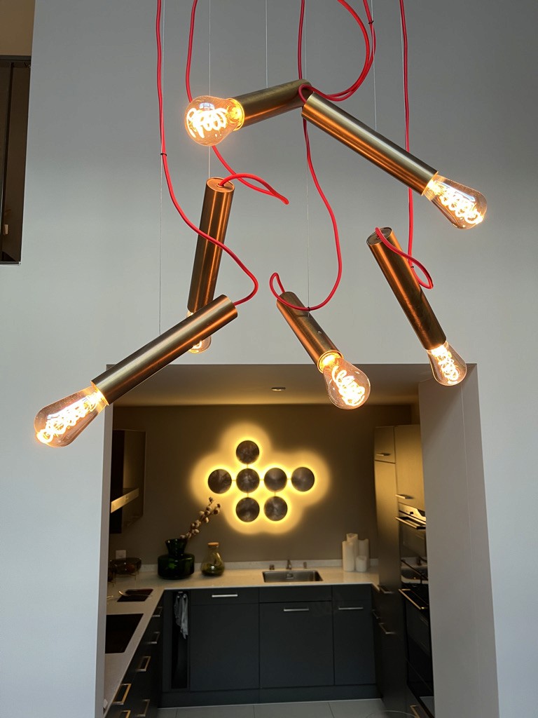 Brass tubular pendant suspended from red cords