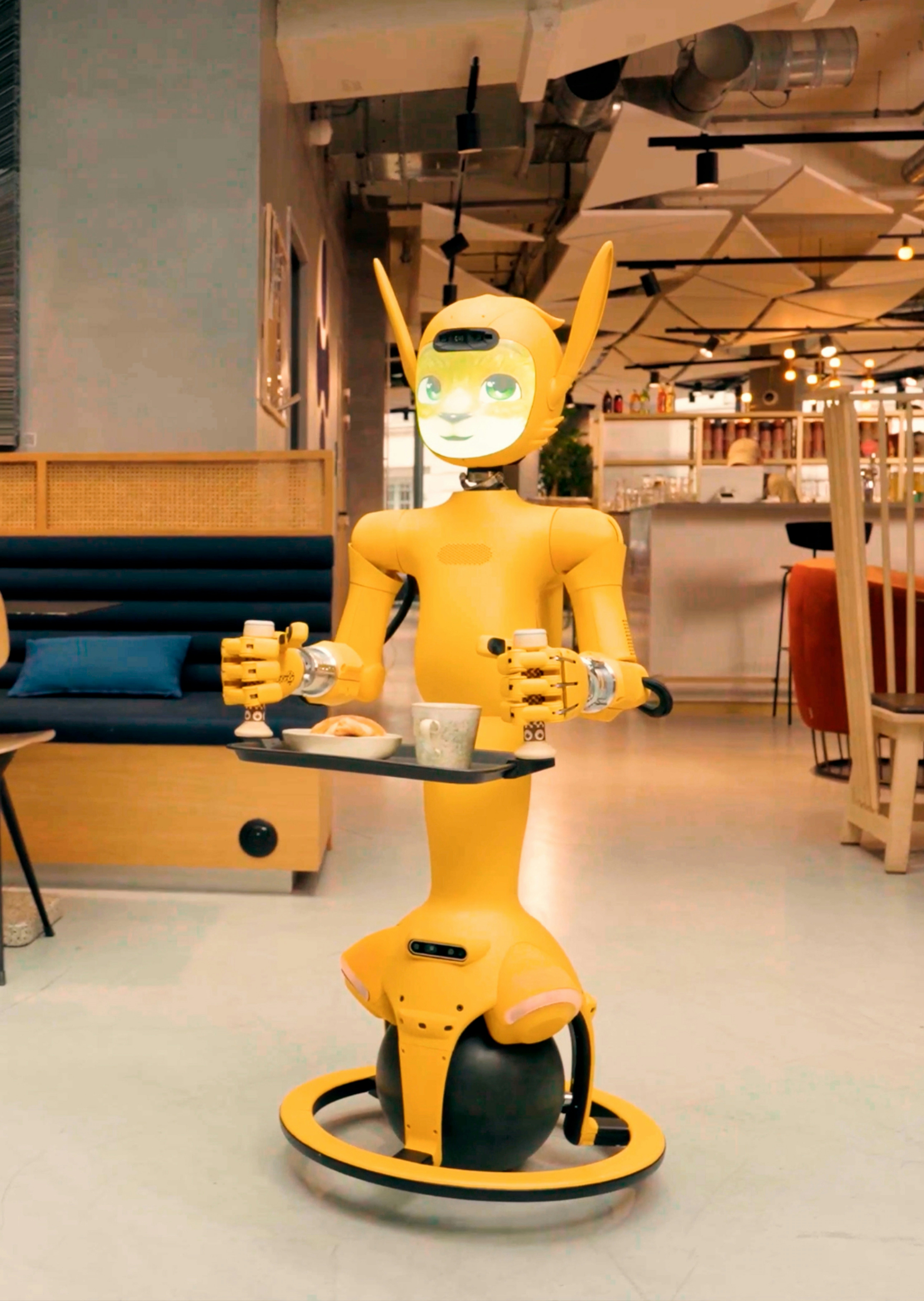 A yellow robot serving drinks and food in a cafe