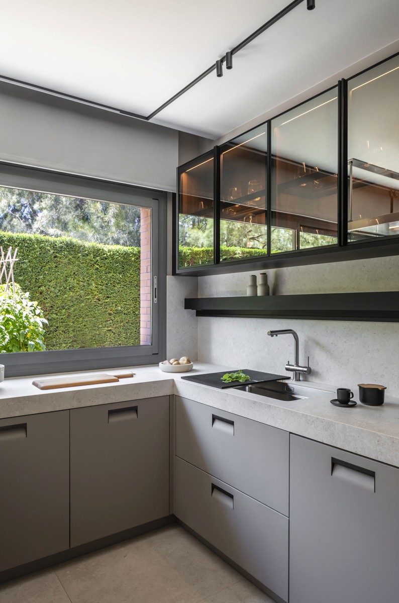 Cocina Arclinea con muebles y encimera en tonos grises y ventana grande al jardín