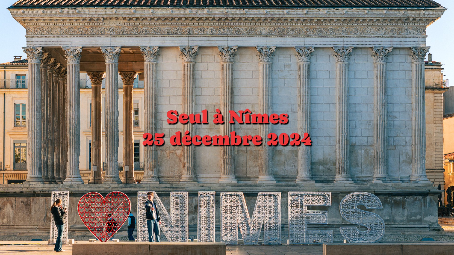 Façade de la Maison Carrée à Nîmes avec une installation lumineuse “I ❤️ NÎMES” au premier plan.