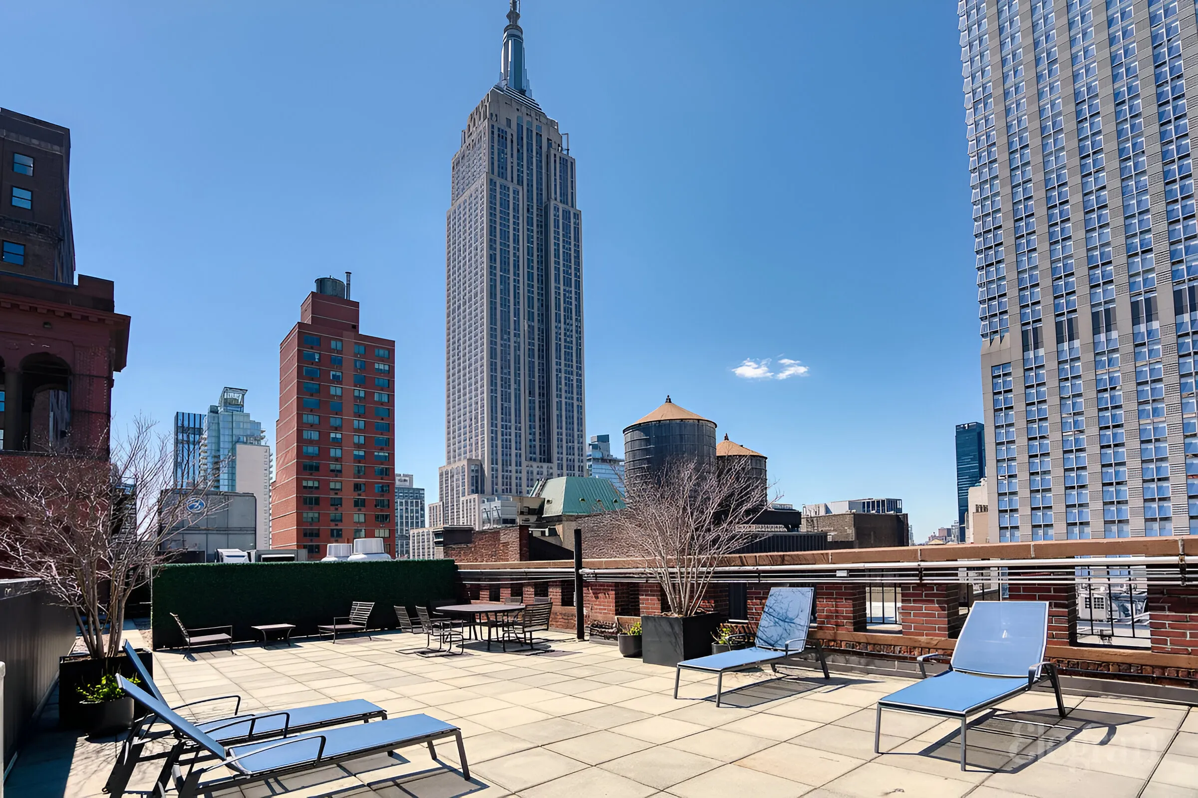 Rooftop patio featuring lounge chairs with a panoramic view of the city skyline in the background.