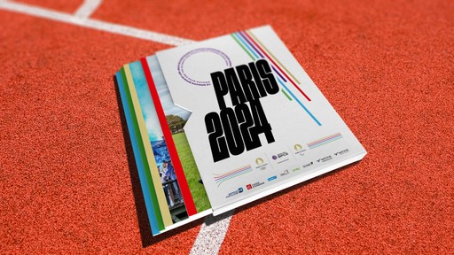 Livre JOP Paris 2024 du groupe BPCE. Le livre est posé sur une piste d'athlétisme rouge et arbore les logos de l'événementet du Groupe BPCE.